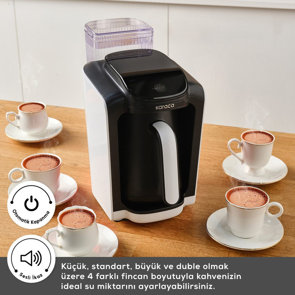 Ahşap masa üzerinde siyah beyaz kahve makinesi, etrafında dört fincan Türk kahvesi.