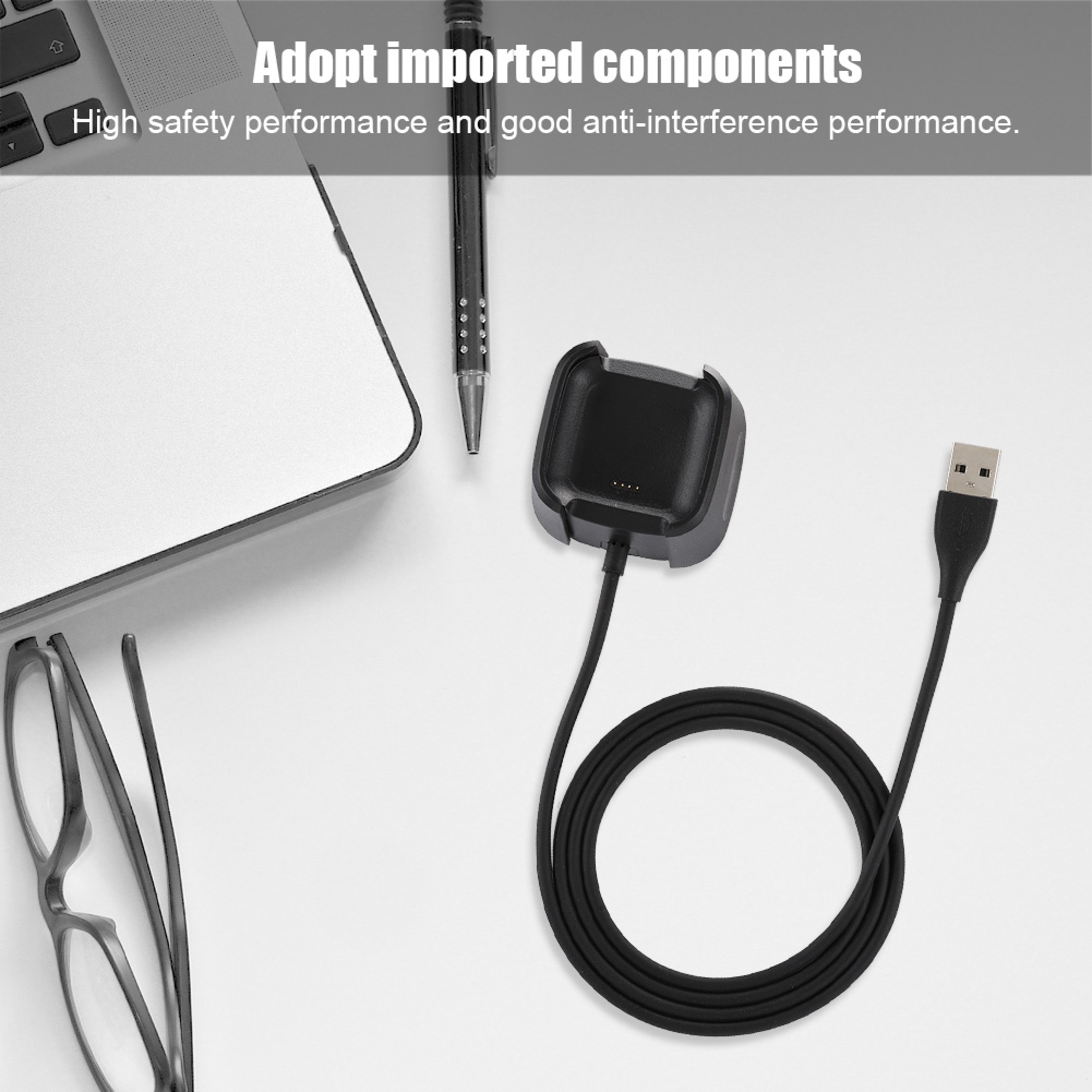 Ladekabel mit USB-Anschluss und Station auf hellem Schreibtisch mit Laptop.