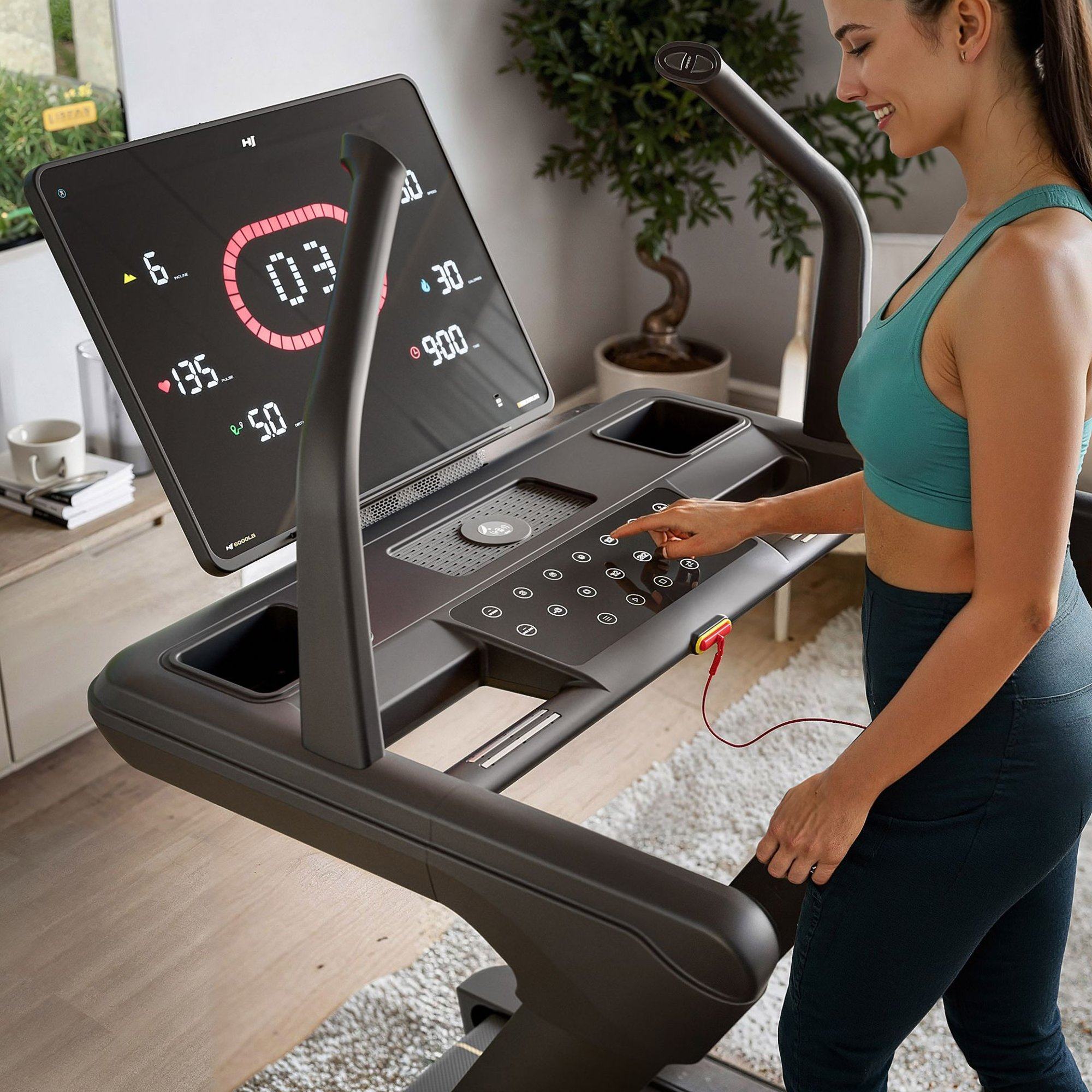 Eine Frau in Sportkleidung steht an einem modernen Laufband mit Touchscreen und bedient das Bedienfeld.