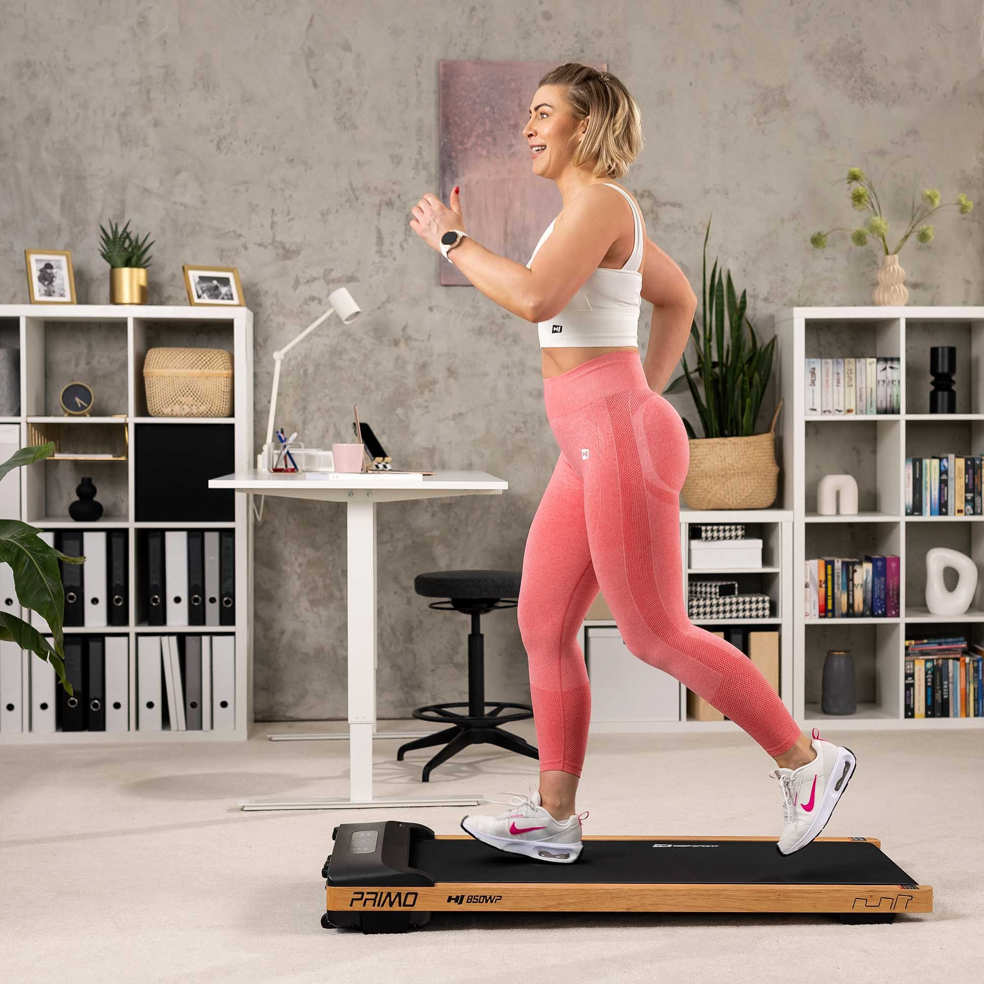 Frau läuft in einem Büro auf einem kompakten Laufband mit Holzakzenten.