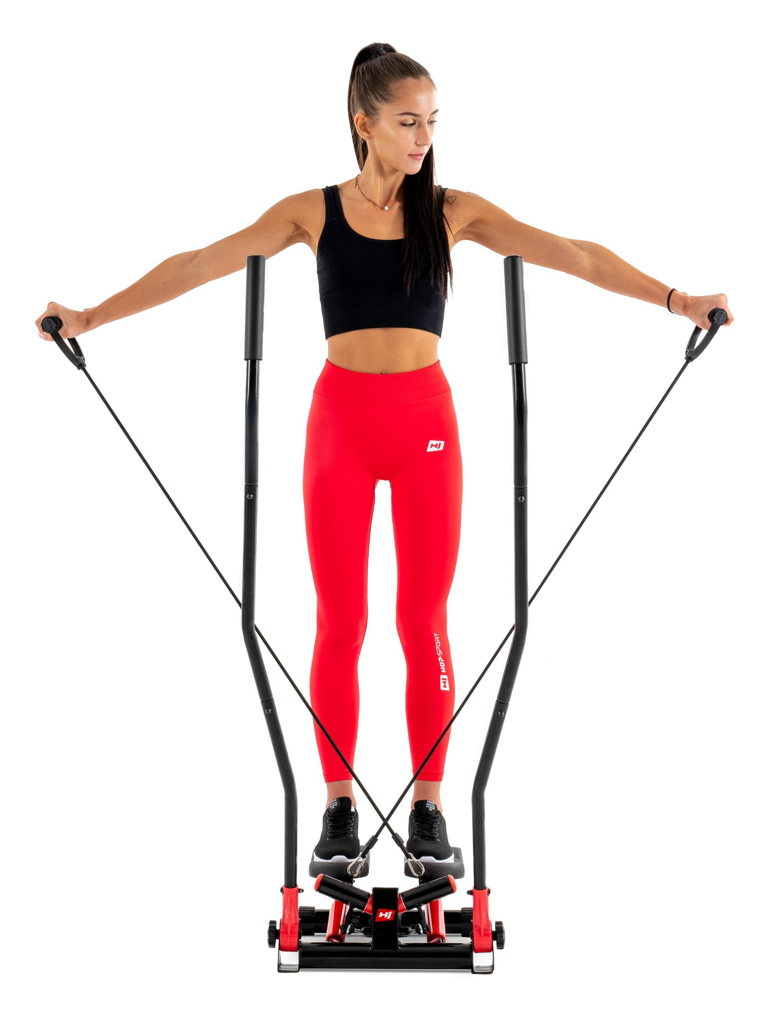 Eine Frau in schwarzem Oberteil und roten Leggings trainiert mit Widerstandsbändern auf einem Fitnessgerät.