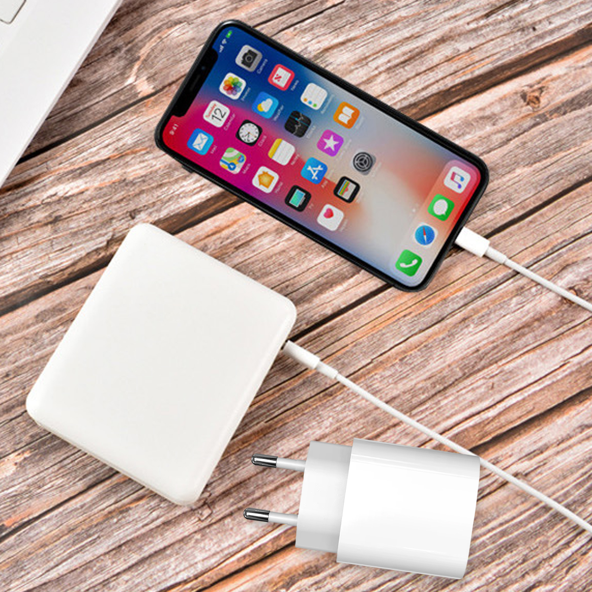 Smartphone, weiße Powerbank und Ladegerät mit Kabel auf hölzernem Tisch.