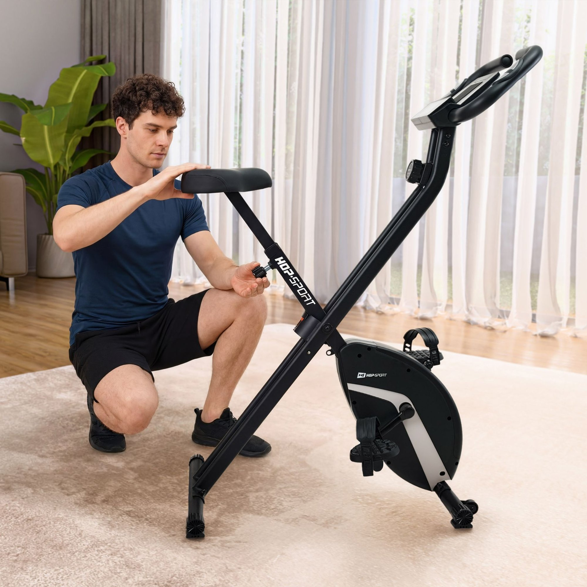 Ein Mann verstellt den Sitz eines schwarzen Heimtrainers auf einem Teppich.