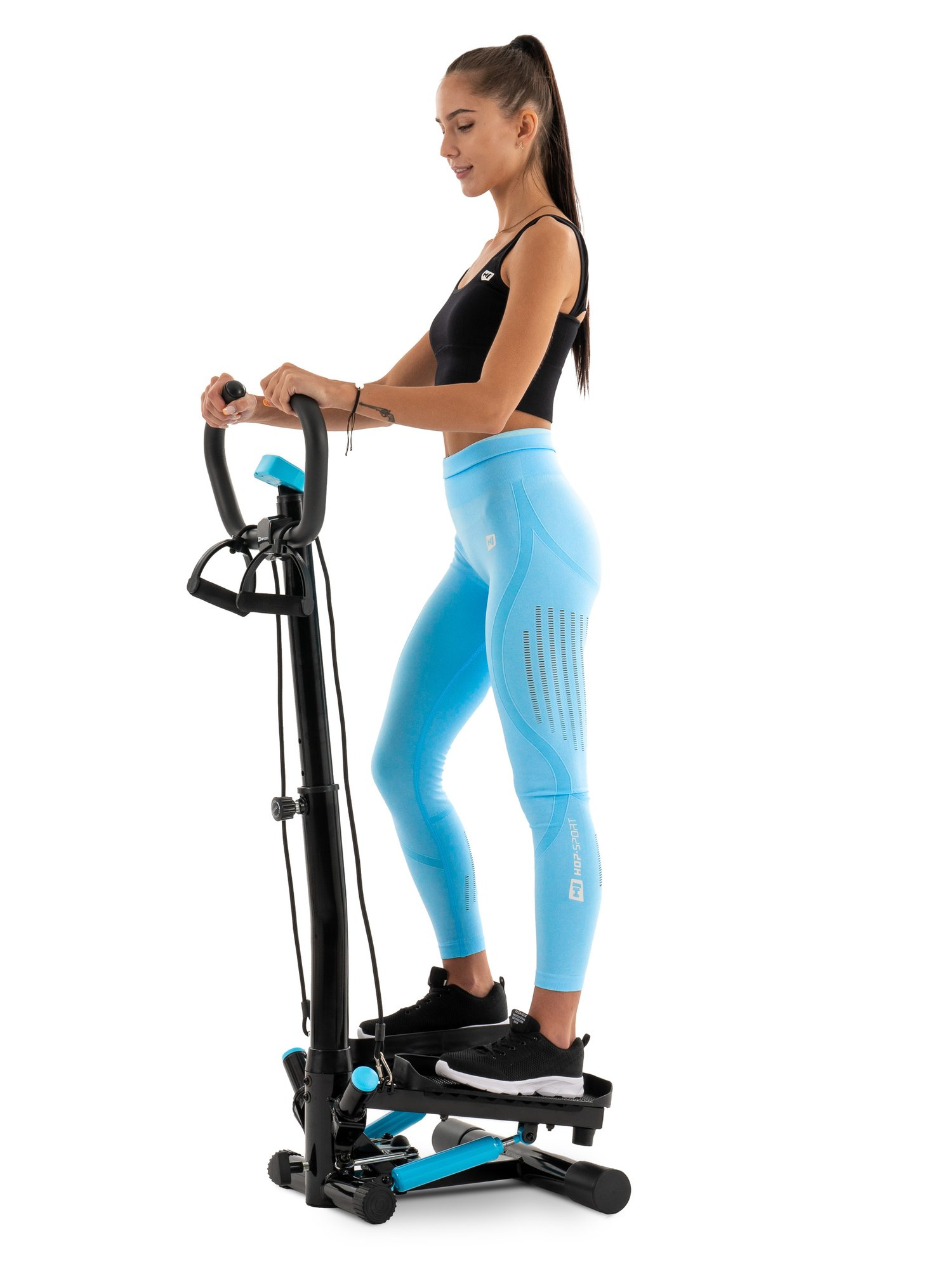 Eine Frau in Sportkleidung trainiert auf einem blauen und schwarzen Stepper vor weißem Hintergrund.