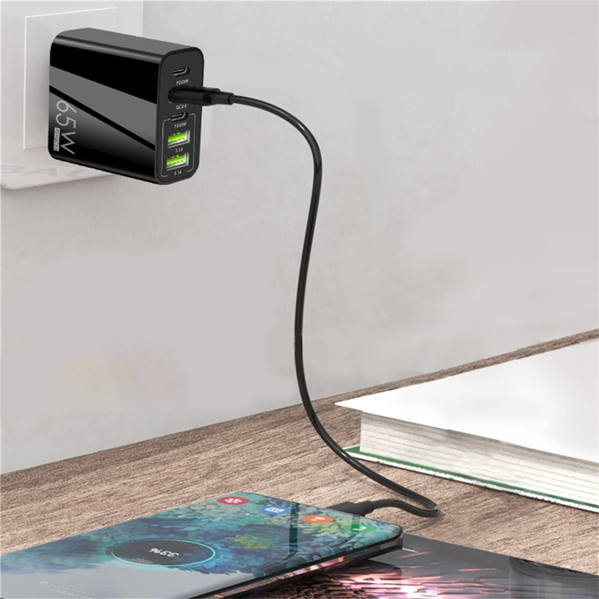 Ein schwarzes 65W-Ladegerät steckt in einer Steckdose und lädt ein Smartphone auf einem Holztisch.