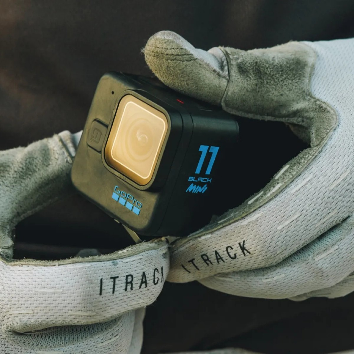 Geflochtene Hände halten eine schwarze GoPro Hero 11 Black Mini Kamera mit blauer Aufschrift.