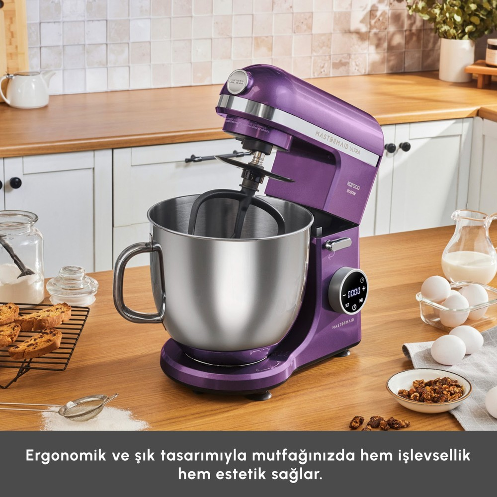 Ahşap tezgah üzerinde metal kaseli mor stand mikser ve çevresinde hamur işi malzemeleri bulunuyor.