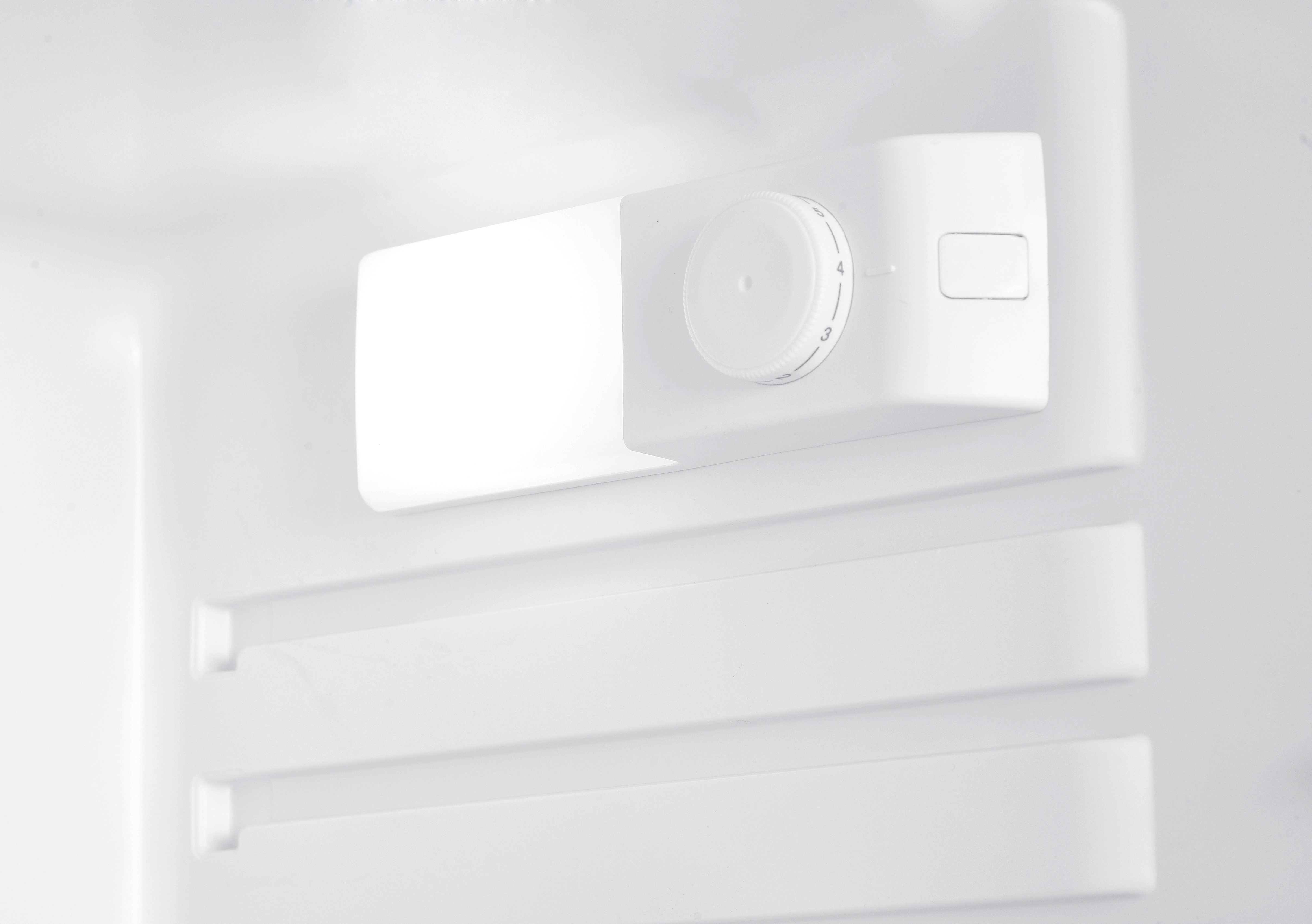 White thermostat dial inside a refrigerator.