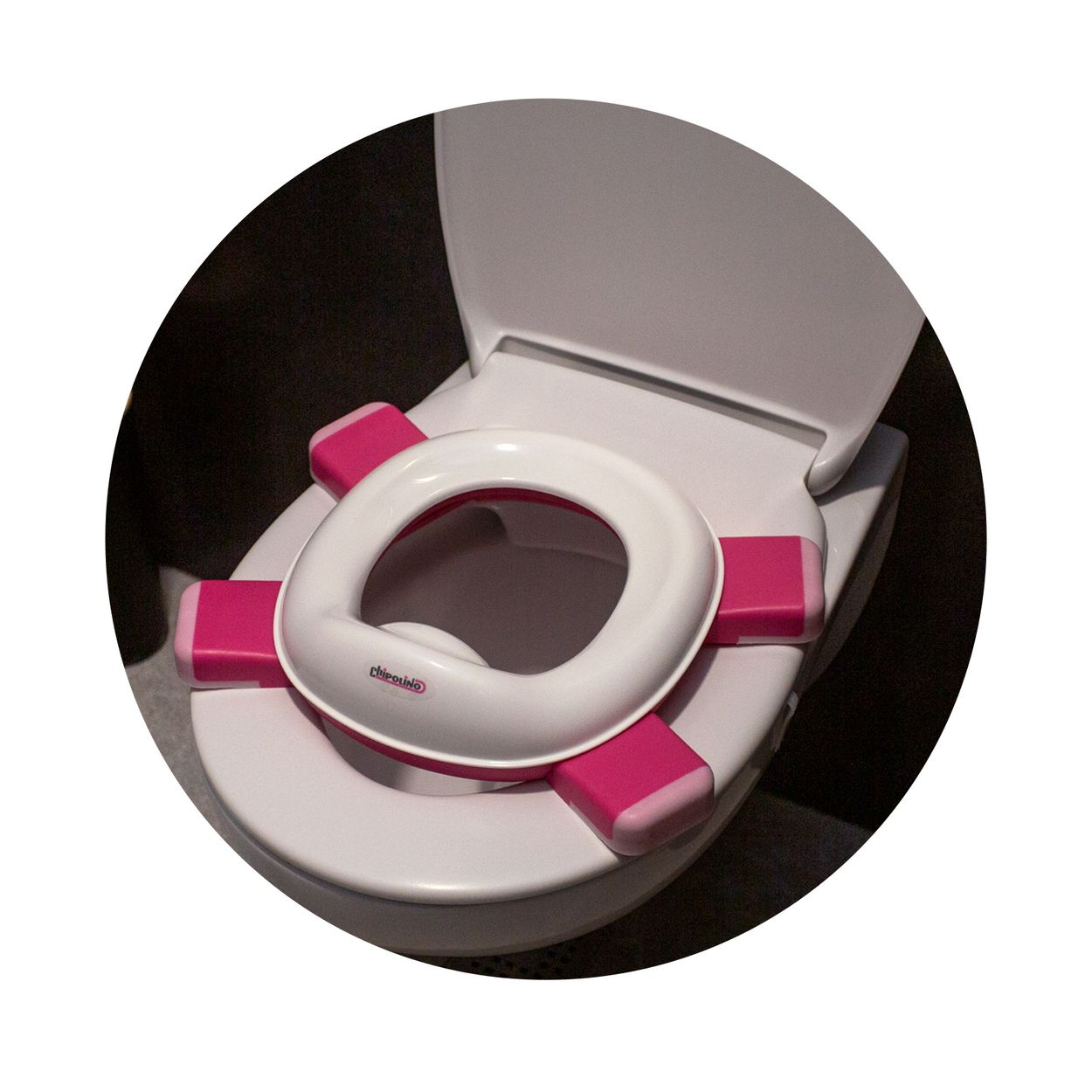 Ein weiß-rosa Toilettensitzaufsatz für Kinder auf einer weißen Toilette.
