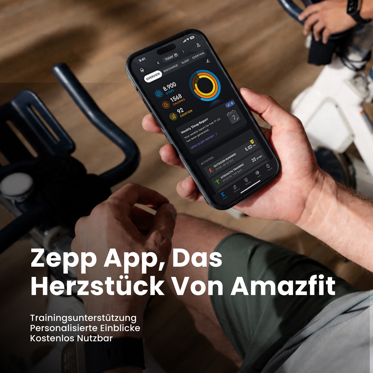 Una persona en una bicicleta estática sostiene un teléfono inteligente con la aplicación Zepp.