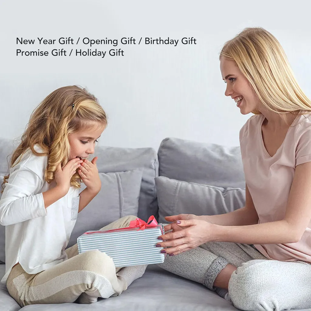 Eine Frau überreicht einem glücklichen Mädchen auf einem grauen Sofa ein Geschenk.