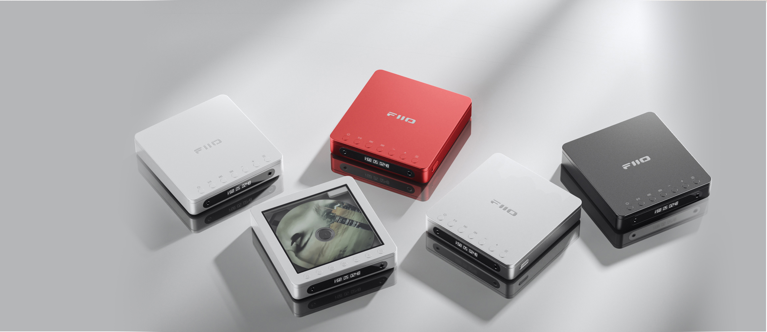 Cinco reproductores de música FIIO en blanco, rojo, plata y negro sobre una superficie gris reflectante.