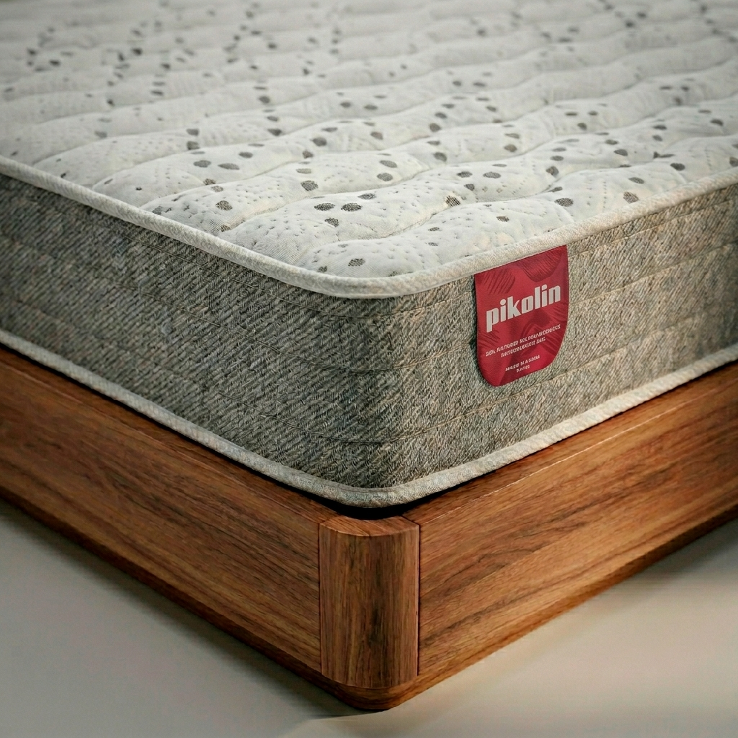 Un colchón acolchado con etiqueta Pikolin está sobre una base de madera.