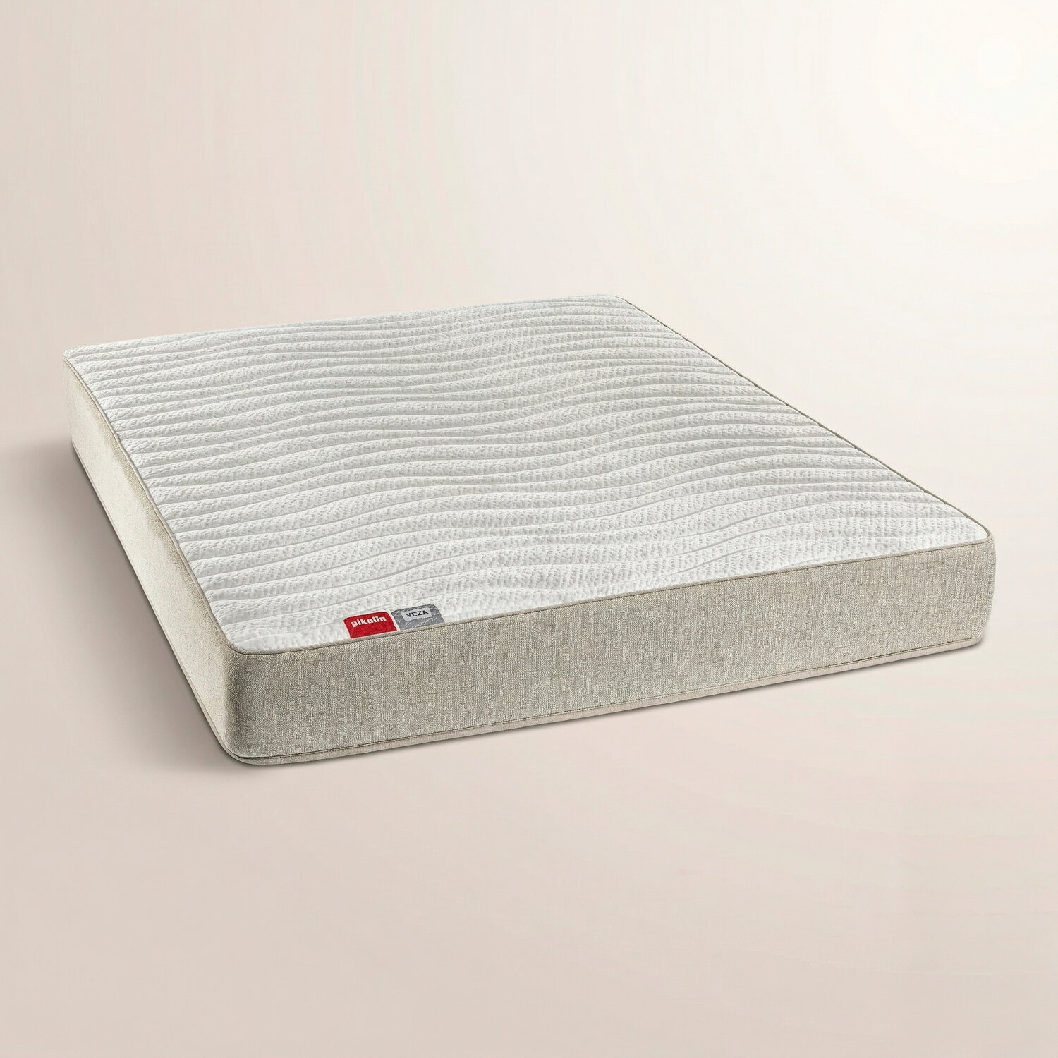 Un colchón blanco con patrón ondulado sobre fondo beige.