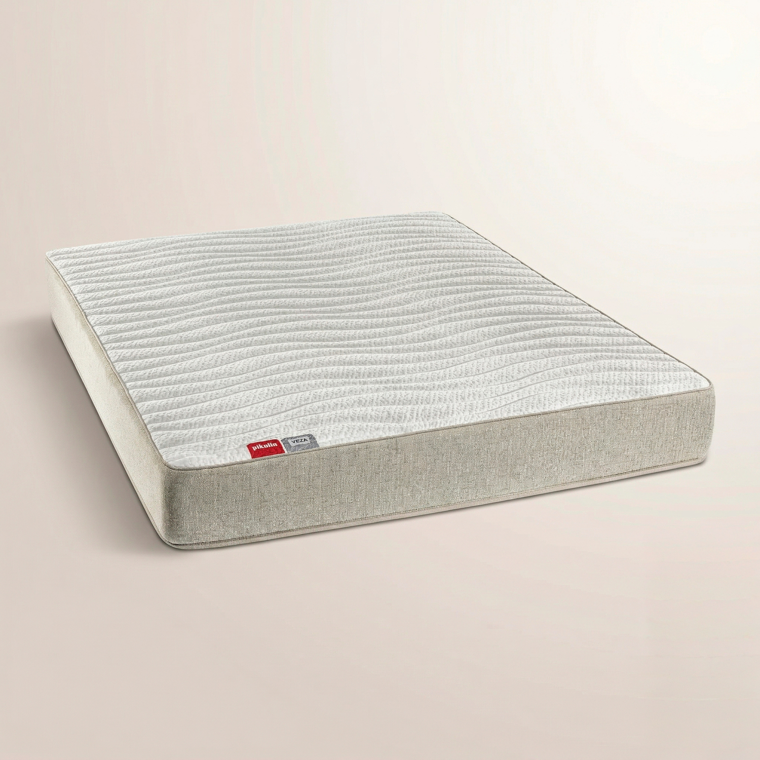 Un colchón blanco y beige con textura ondulada sobre un fondo neutro.