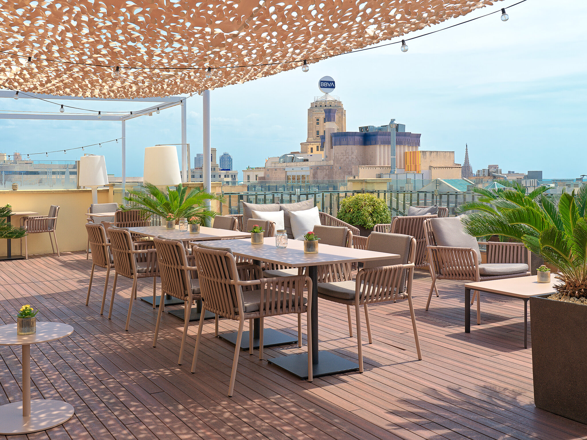 Soleada terraza en la azotea con suelo de madera, muebles de comedor modernos y vistas a la ciudad.