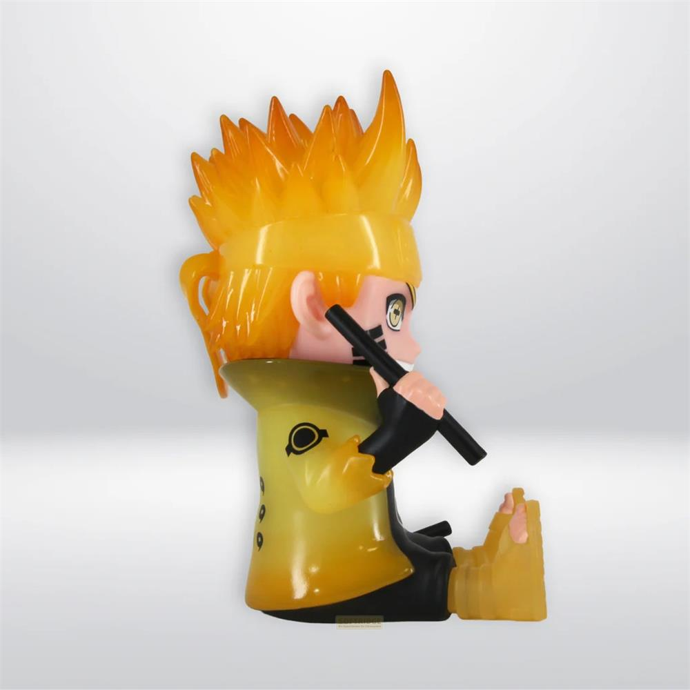 Una figura de anime amarilla con cabello puntiagudo está sentada de perfil, sosteniendo un bastón negro.