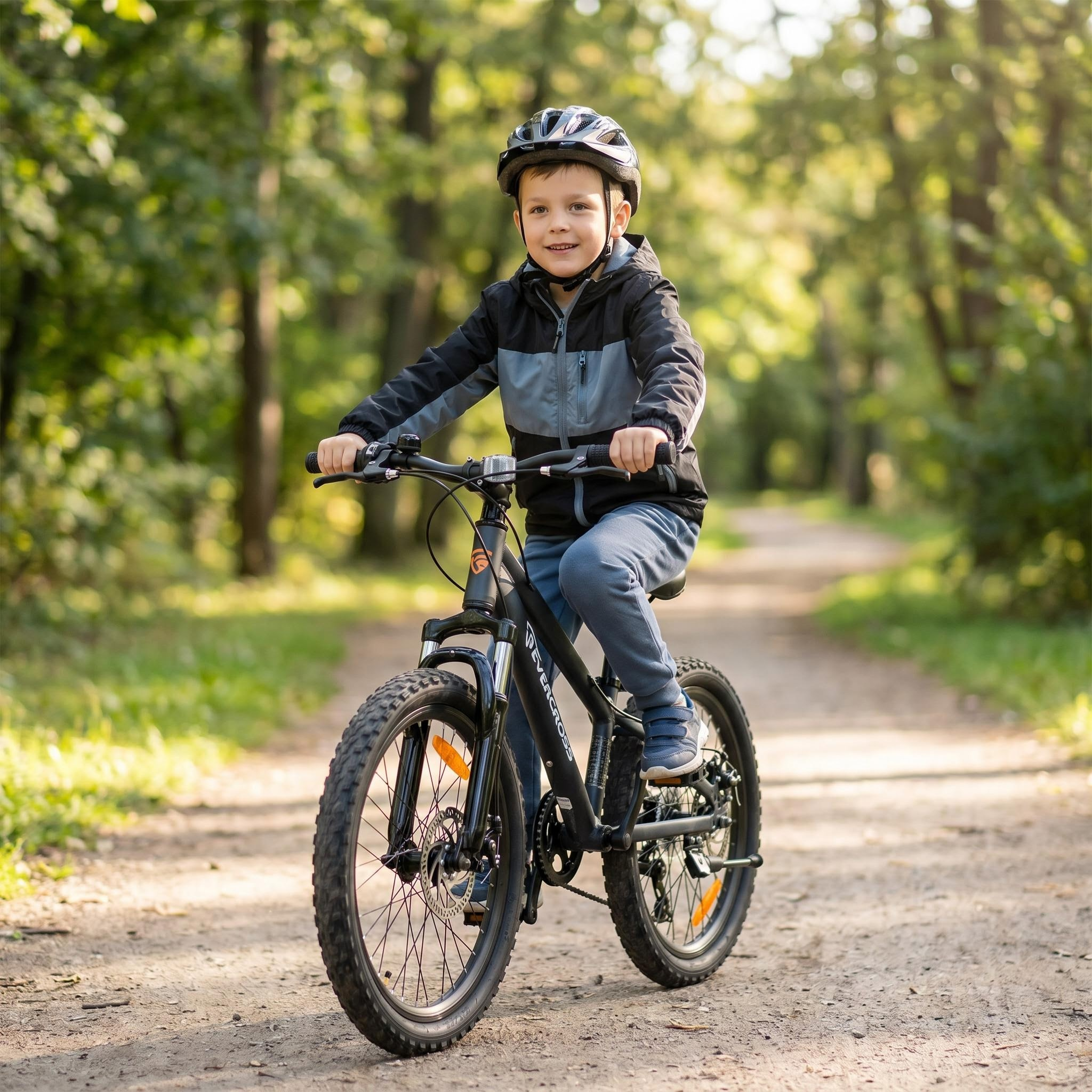 Ein Junge mit Helm fährt auf einem Waldweg ein schwarzes Fahrrad.