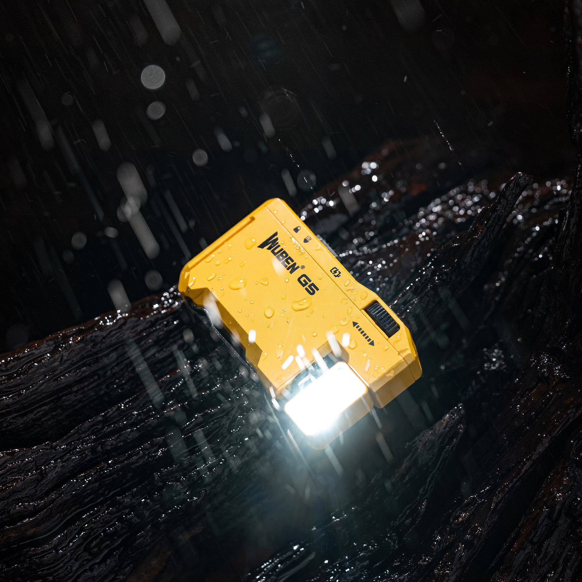 Eine gelbe Wuben G5 Taschenlampe liegt bei starkem Regen auf nassem, dunklem Holz, ihr helles Licht durchbricht den Schauer.