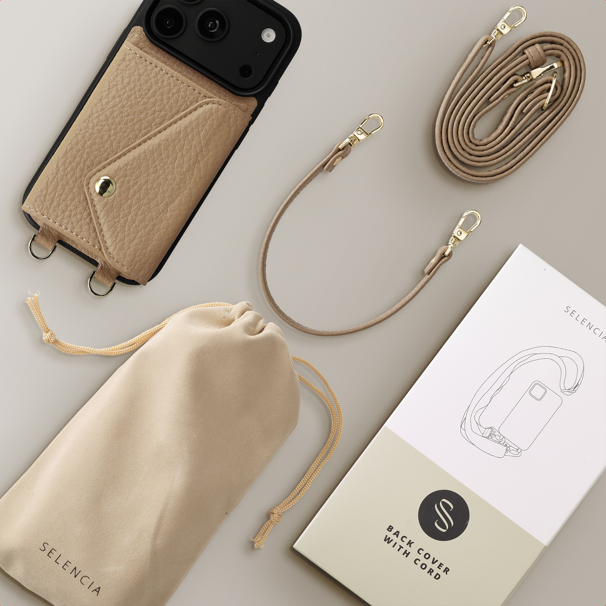Beigefarbene Handyhülle mit Tasche, Umhängegurten, Beutel und Verpackung auf grauem Hintergrund.