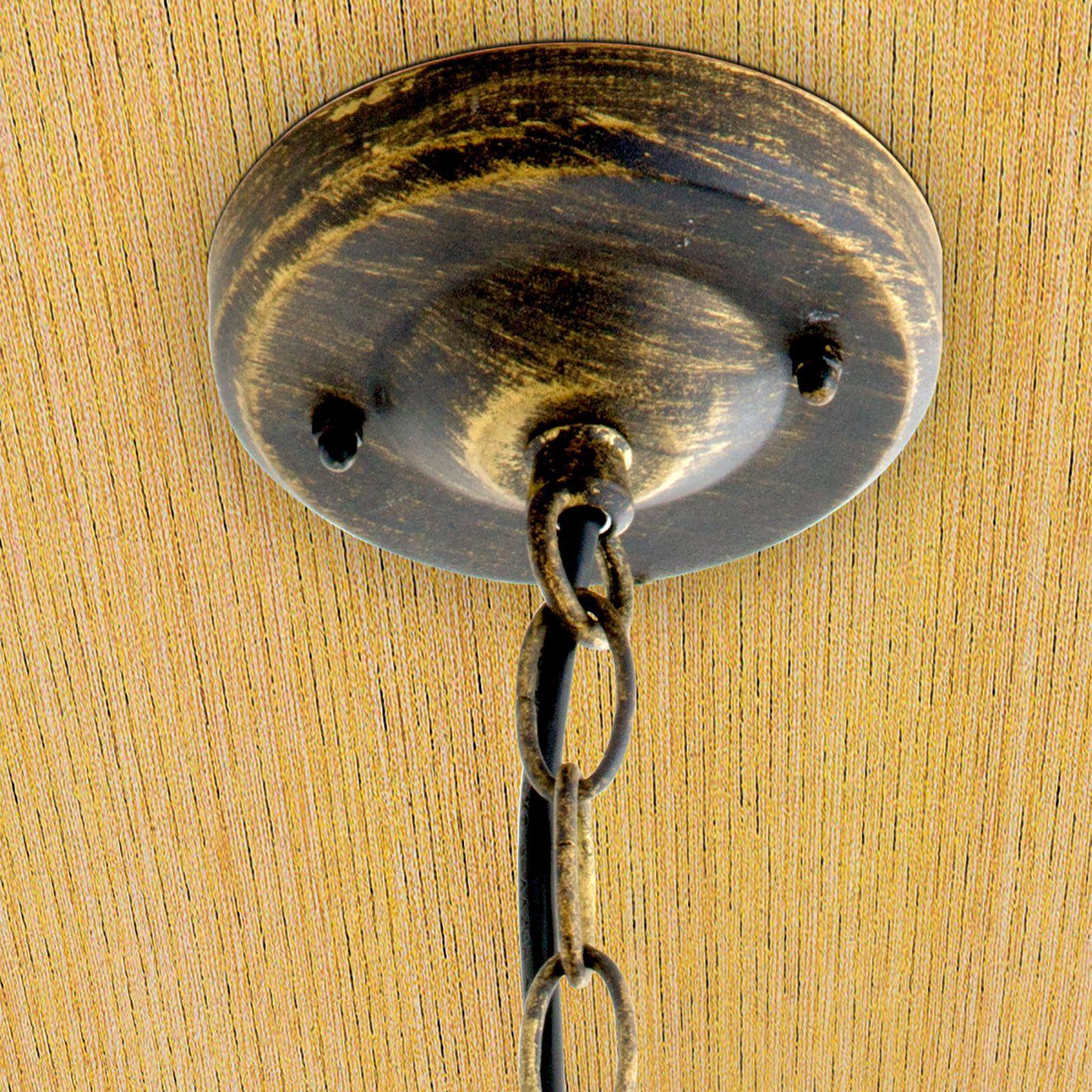 Eine bronzefarbene Deckenrosette mit angehängter Kette an einer holzfarbenen Decke.