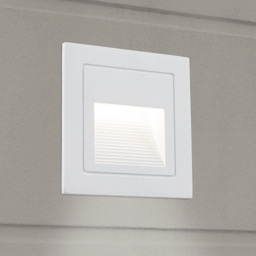 Eine weiße quadratische Wandleuchte ist in eine graue Wand eingelassen und strahlt sanftes Licht aus.