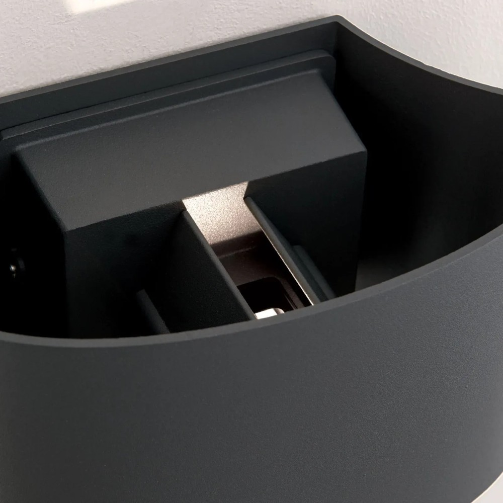 Eine schwarze Wandleuchte mit modernem Design, die an einer weißen Wand montiert ist.