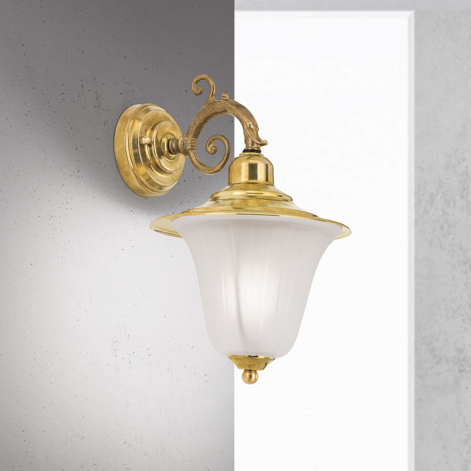 Antike Messing-Wandlampe mit weißem Glasschirm an einer grauen Wand.