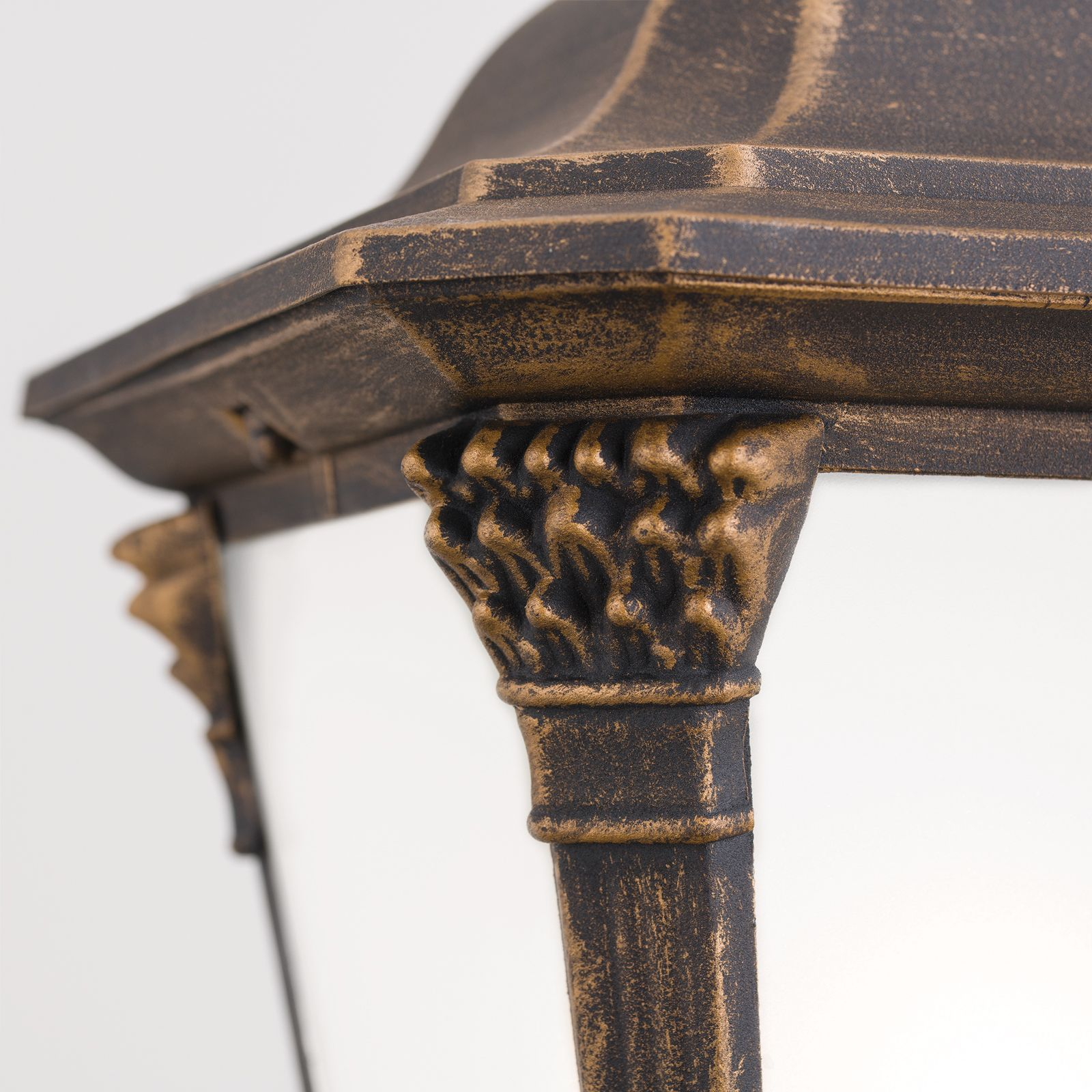 Nahaufnahme einer bronzenen und schwarzen dekorativen Außenlampe mit verzierten Säulen vor weißem Hintergrund.