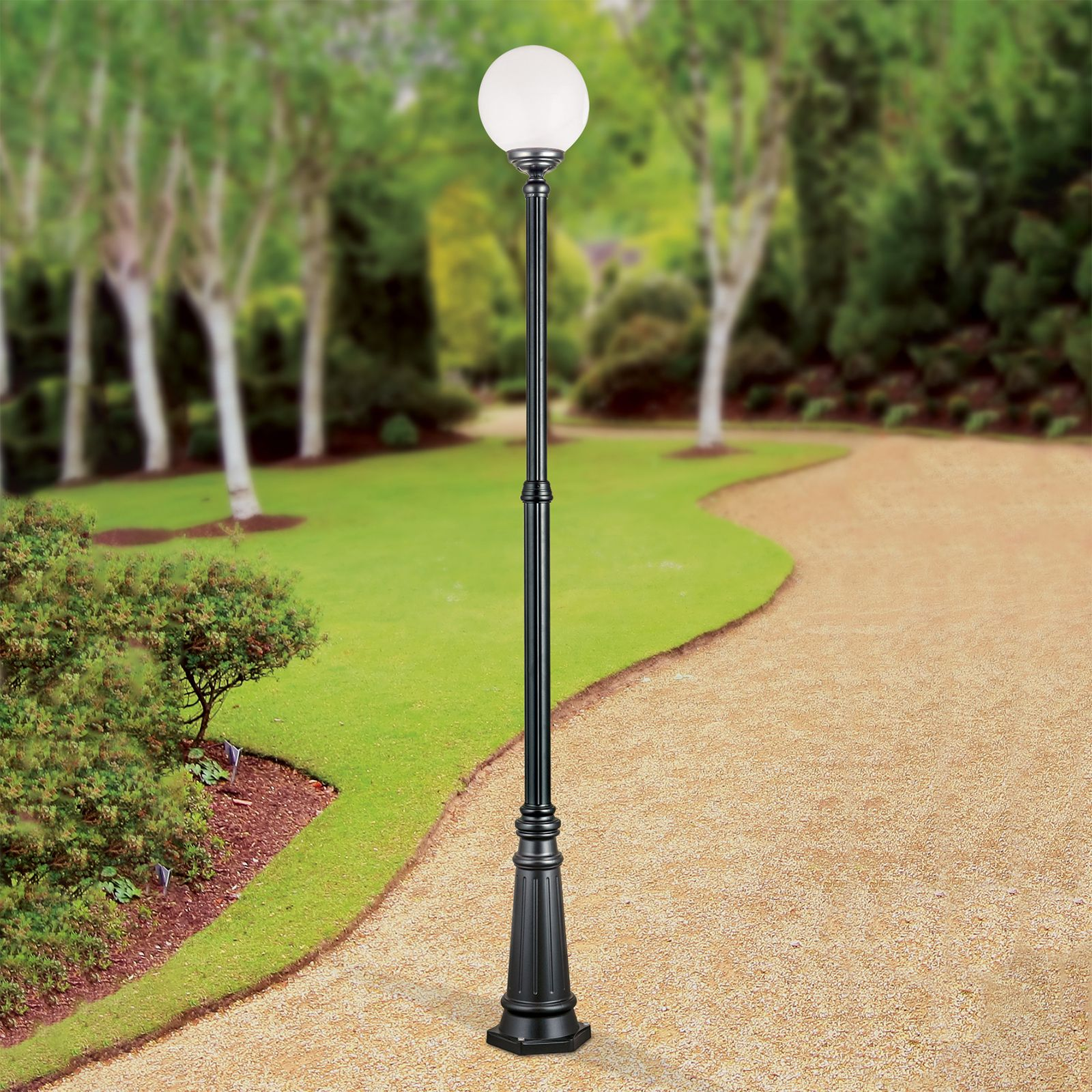 Eine schwarze Laterne mit einer kugelförmigen weißen Lampe steht auf einem Kiesweg in einem Park mit grünem Gras und Bäumen.