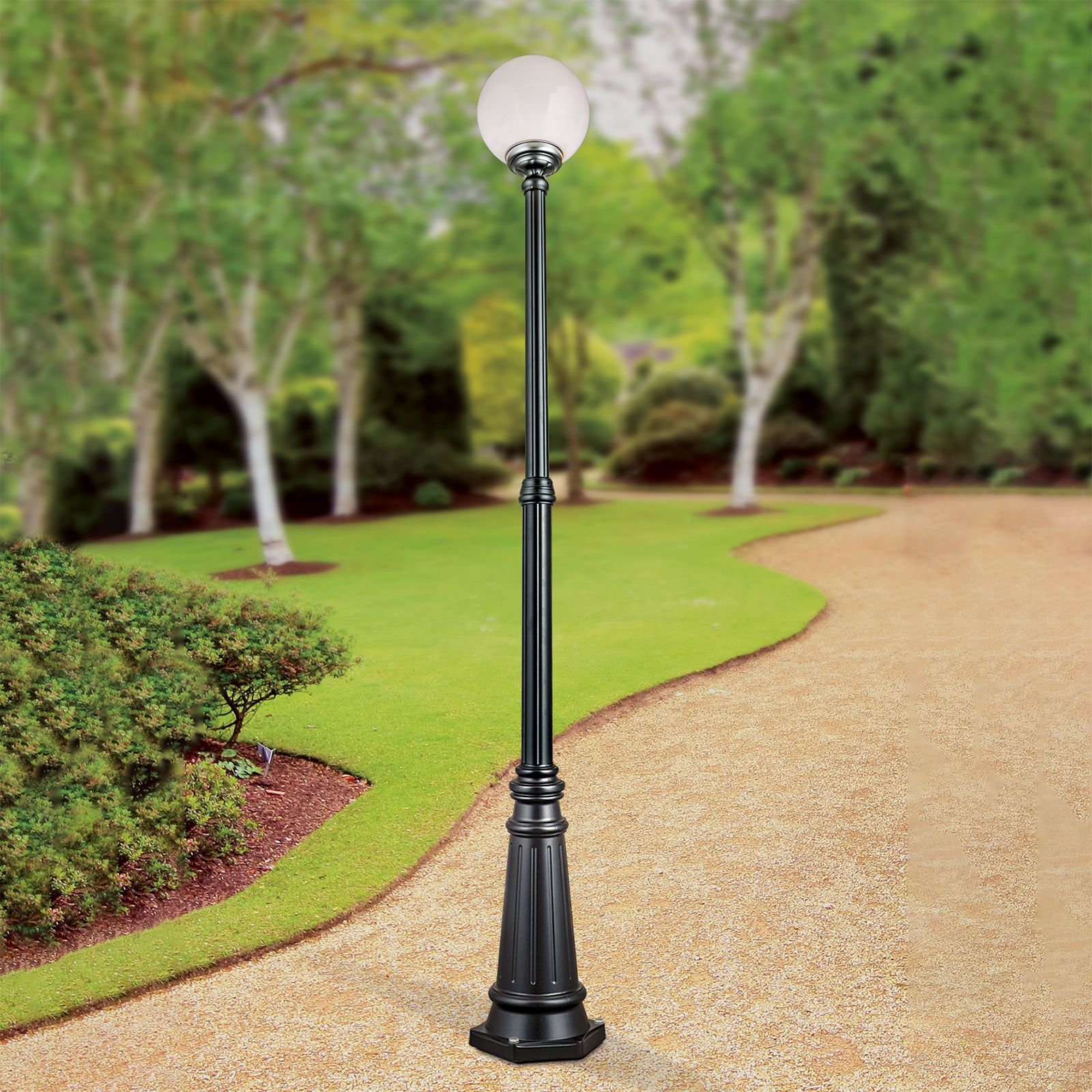 Eine schwarze Standlaterne mit weißer Kugelstehlampe steht auf einem Gartenweg.