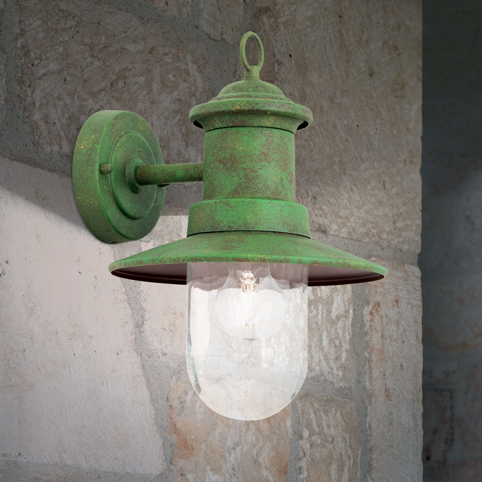 Eine grüne Wandleuchte im Vintage-Stil mit klarem Glas und sichtbarer Glühbirne an einer Natursteinwand.