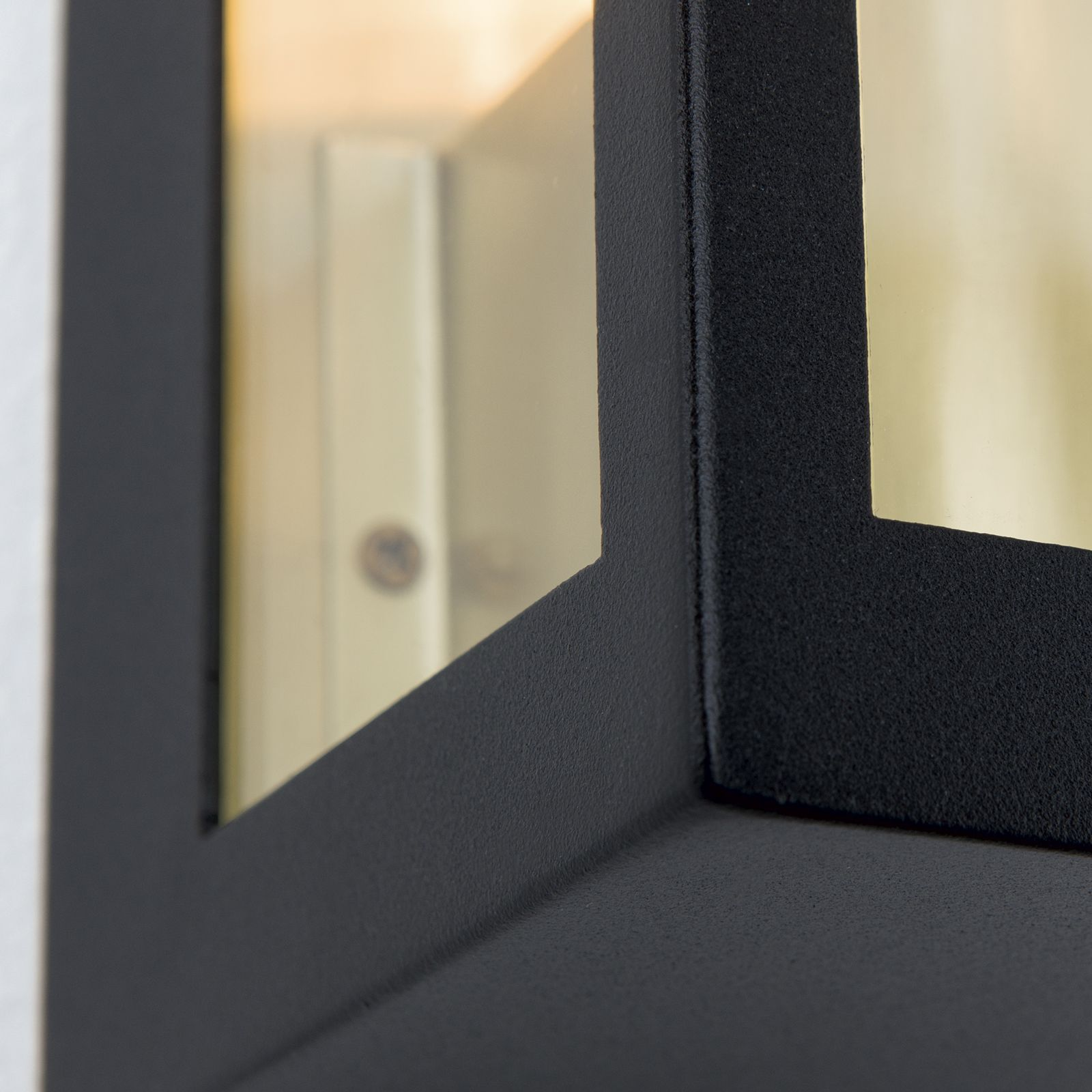 Nahaufnahme einer schwarzen, modernen Wandleuchte mit Glas und Metall.