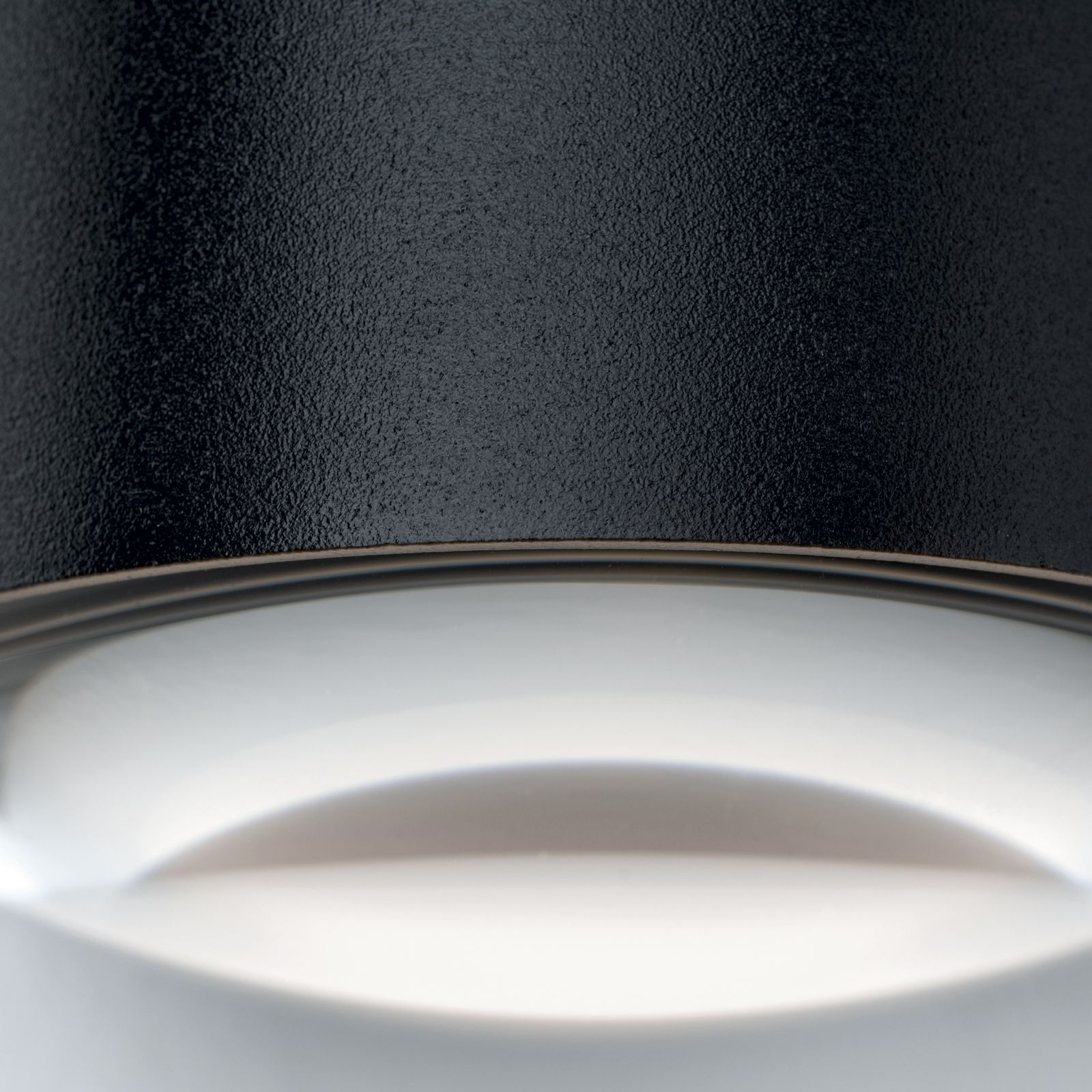 Nahaufnahme einer schwarzen, strukturierten Lampe mit weißem Lichtschein.
