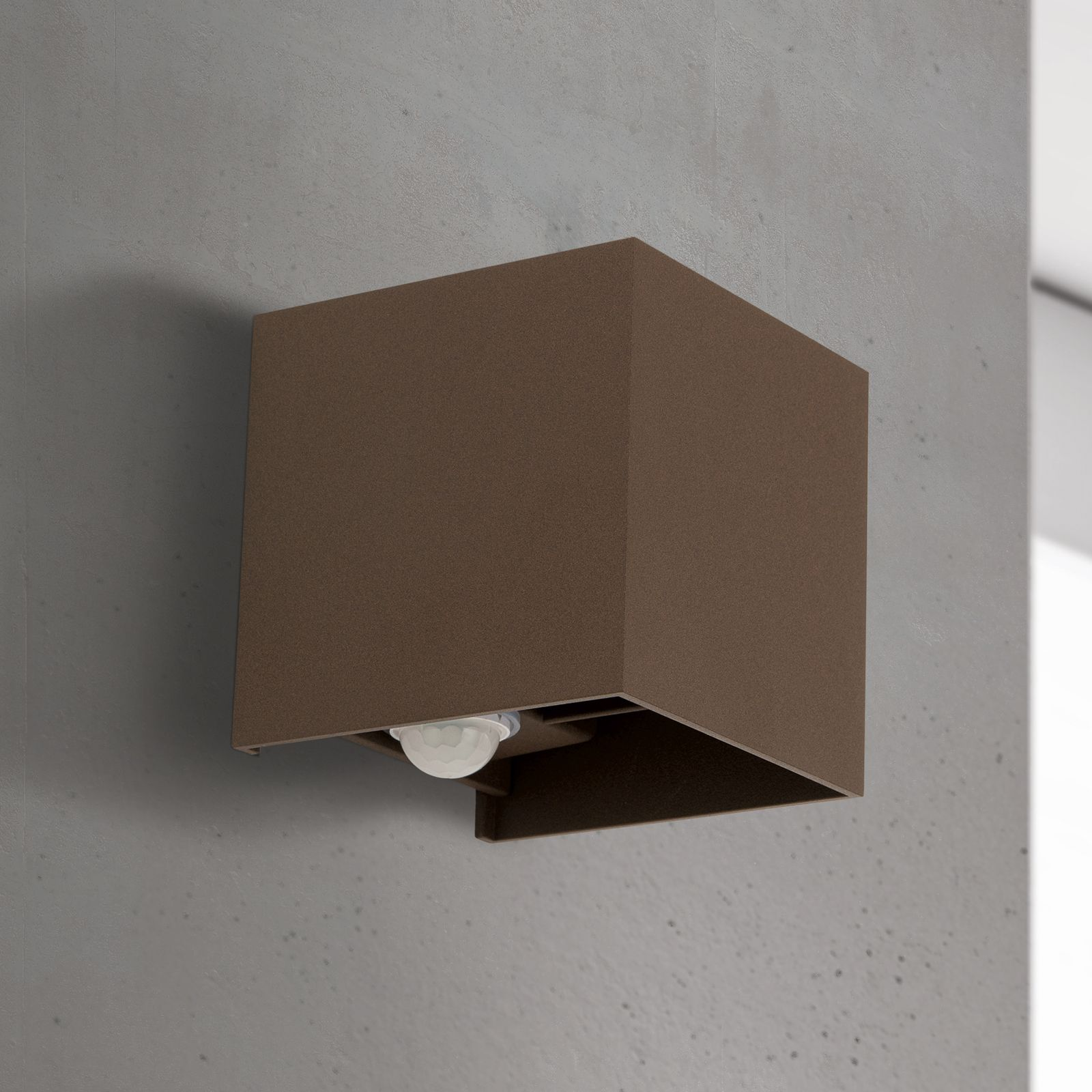 Eine moderne braune quadratische Wandleuchte mit Bewegungsmelder unten, montiert an einer grauen Betonwand.
