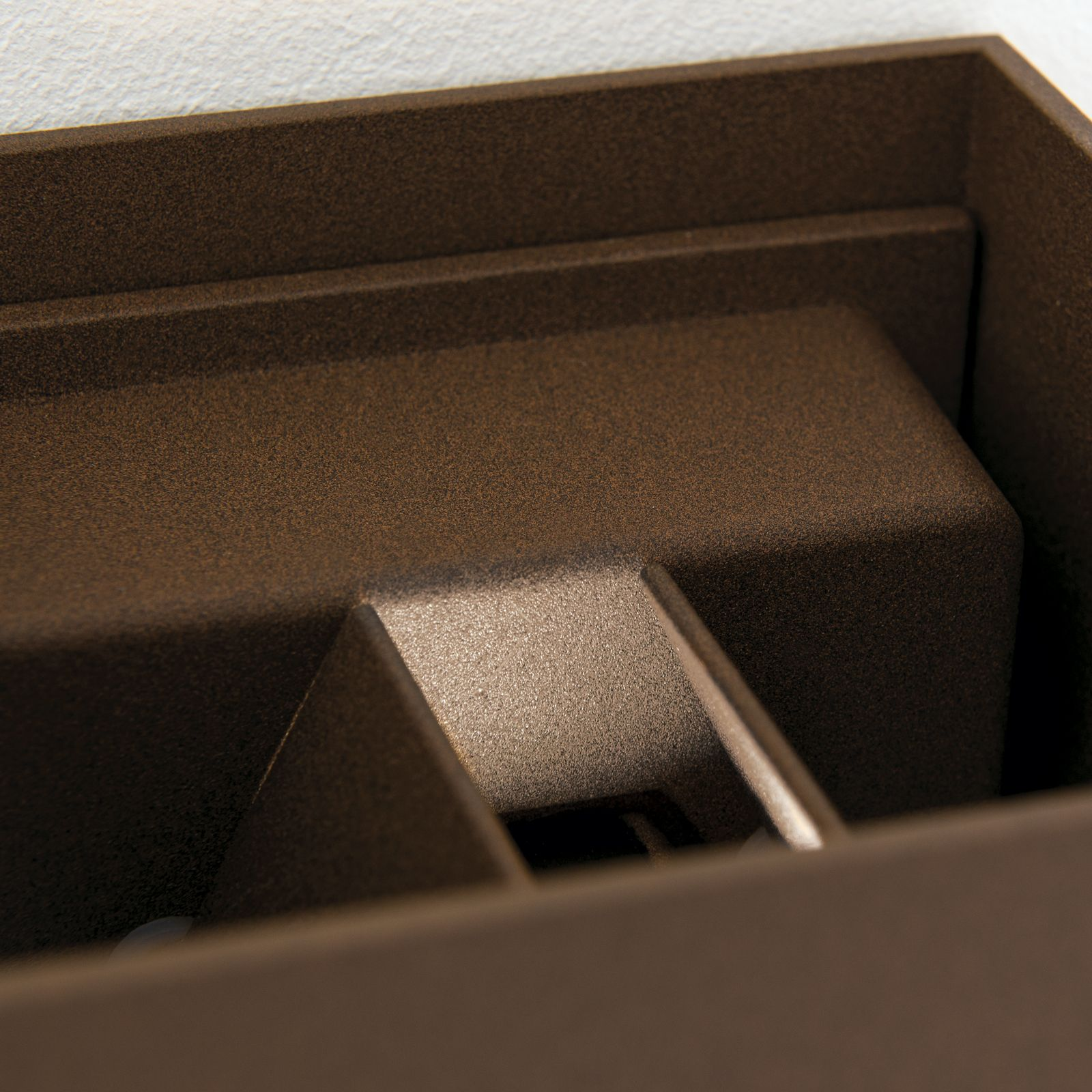 Eine matte, braune Wandleuchte mit geometrischem Design und integrierter Lichtöffnung.
