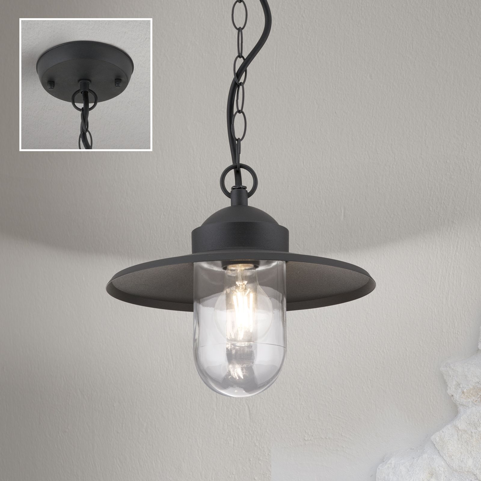 Eine schwarze Hängelampe mit Glasschirm und Kette an einer hellen Wand, Inset zeigt Deckenhalterung.