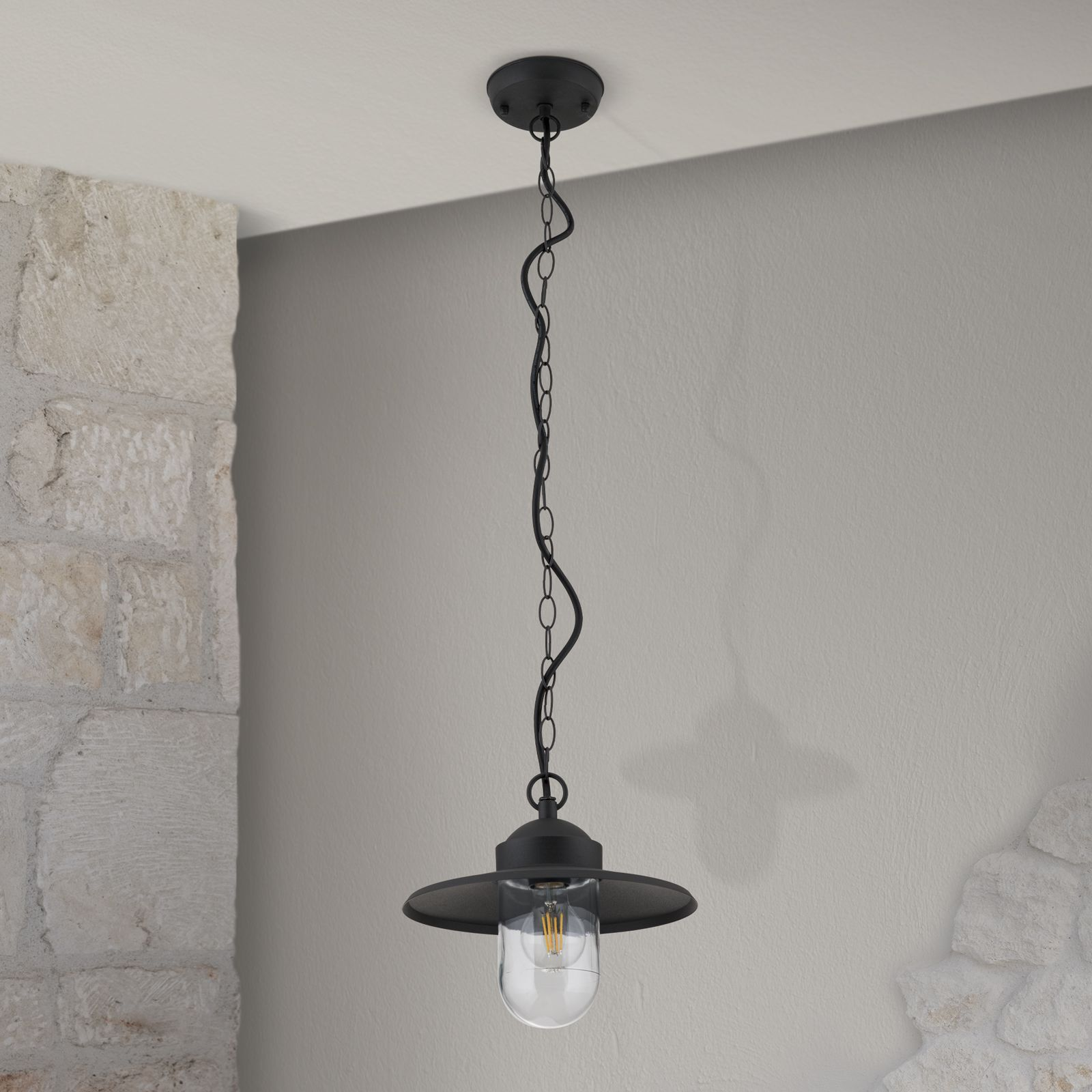 Schwarze Hängeleuchte mit Kette, transparentem Glas und Edison-Glühbirne vor heller Wand.