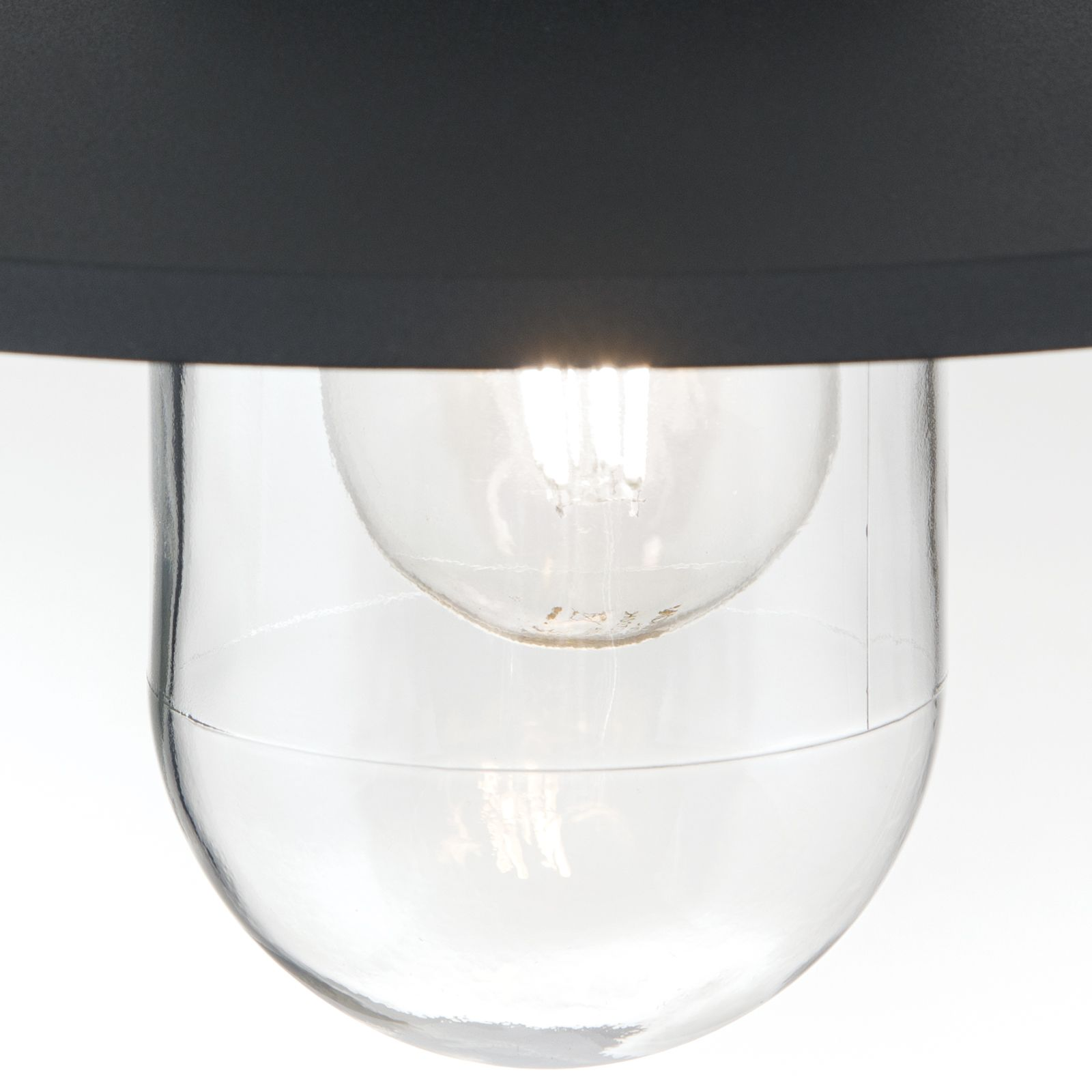 Nahaufnahme einer modernen Pendelleuchte mit schwarzem Schirm und Glasgehäuse mit leuchtender Glühlampe.