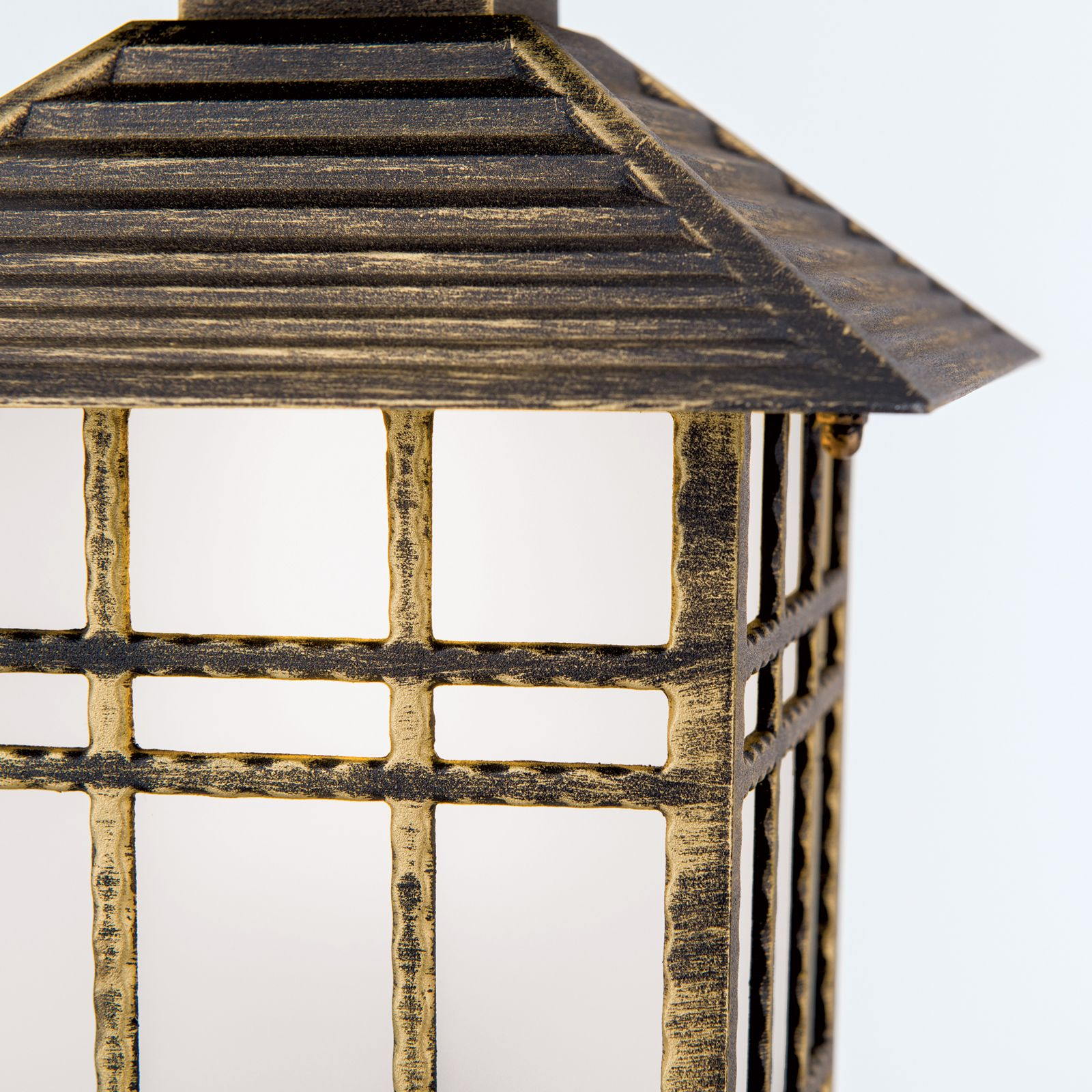 Eine schwarze und goldene Außenlampe mit quadratischen Glasfenstern und einem gerippten Metalldach.