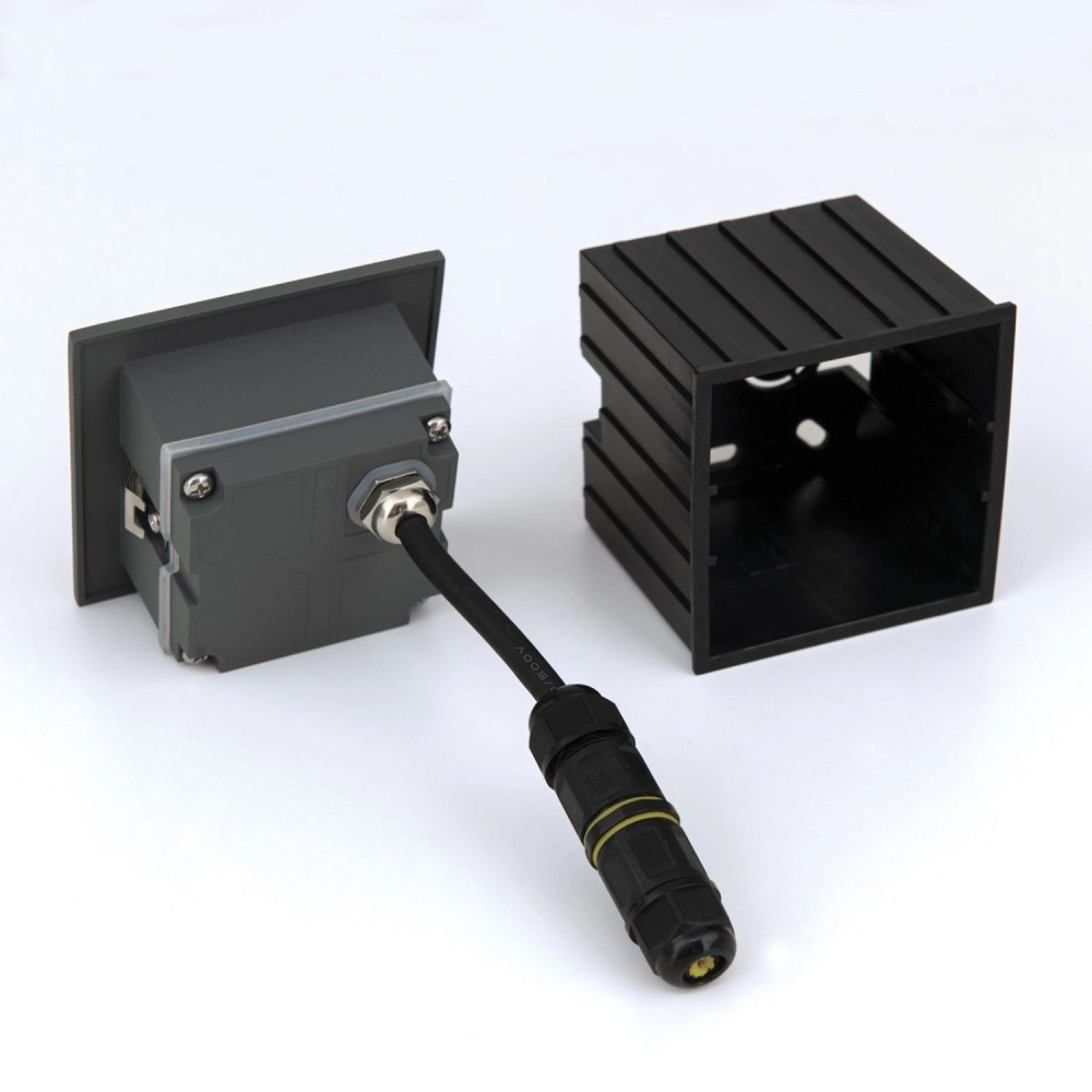 Eine graue Unterputzdose mit angeschlossenem schwarzem Kabel und Stecker sowie eine schwarze Einbauhülse.