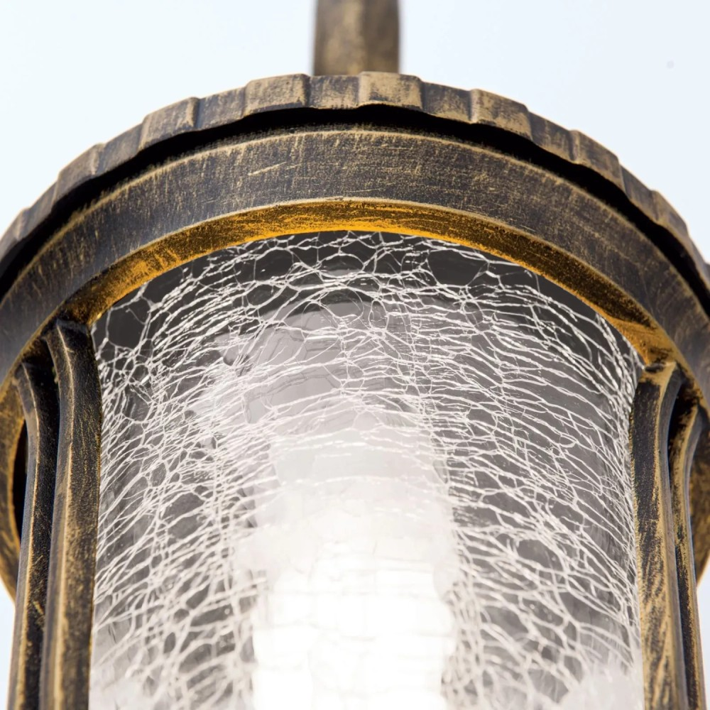 Antike Bronzelaterne mit dekorativem Rissglas-Design und warmem Innenlicht vor hellem Hintergrund.