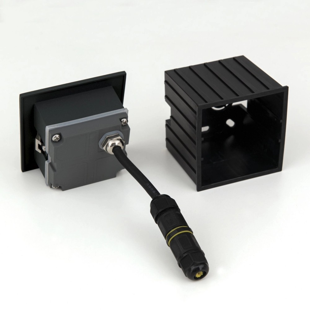 Einbau-Leuchtengehäuse mit angeschlossenem Kabel und Stecker auf heller Oberfläche.