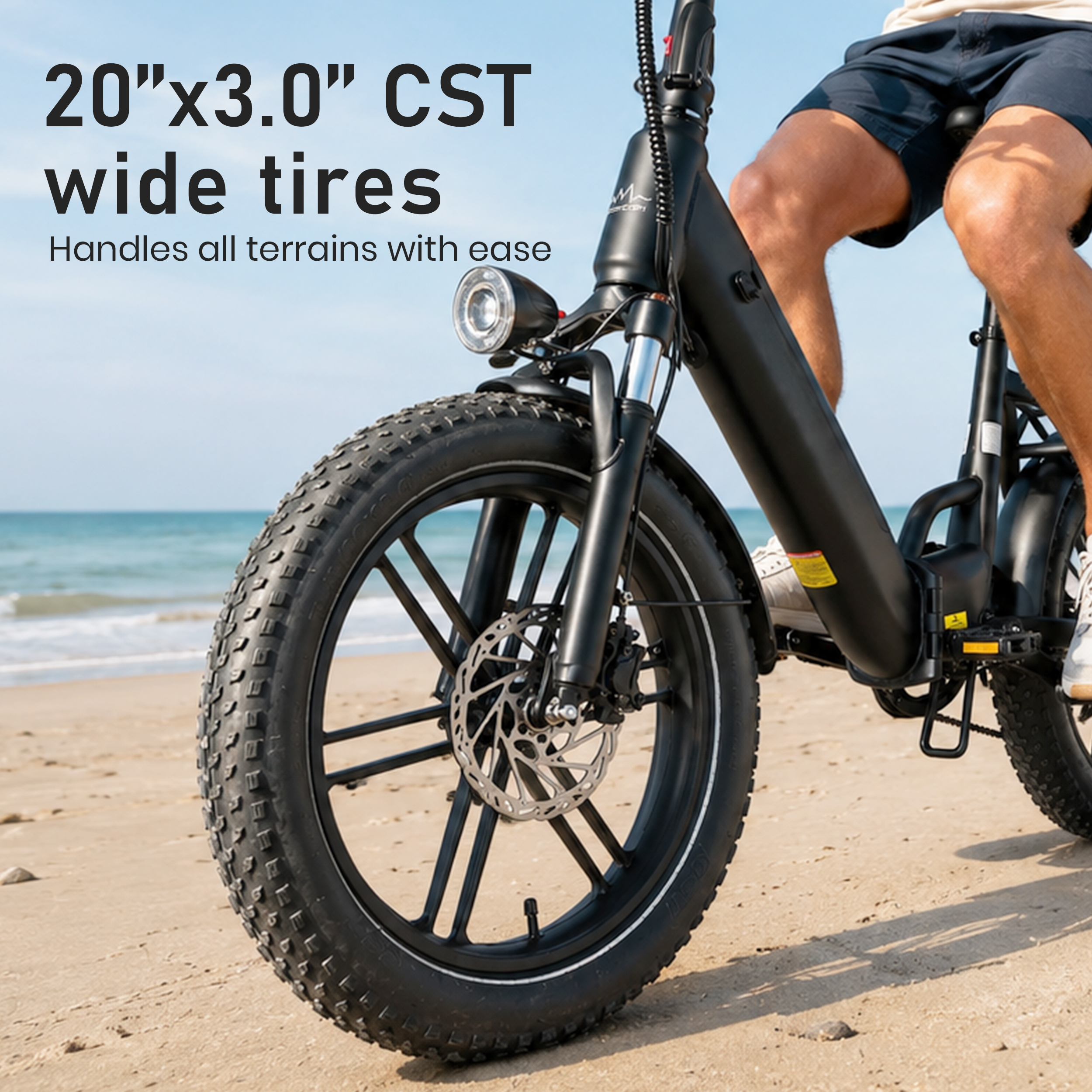 Eine Person fährt auf einem sandigen Strand ein schwarzes E-Bike mit breiten Reifen.