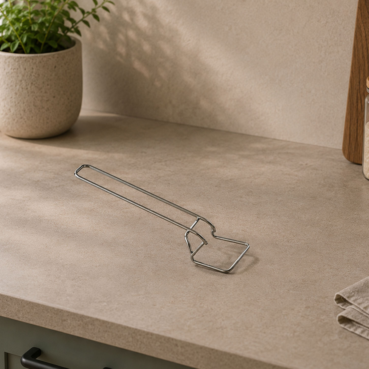 Un soporte para sartenes de metal plateado descansa sobre una encimera de cocina clara.