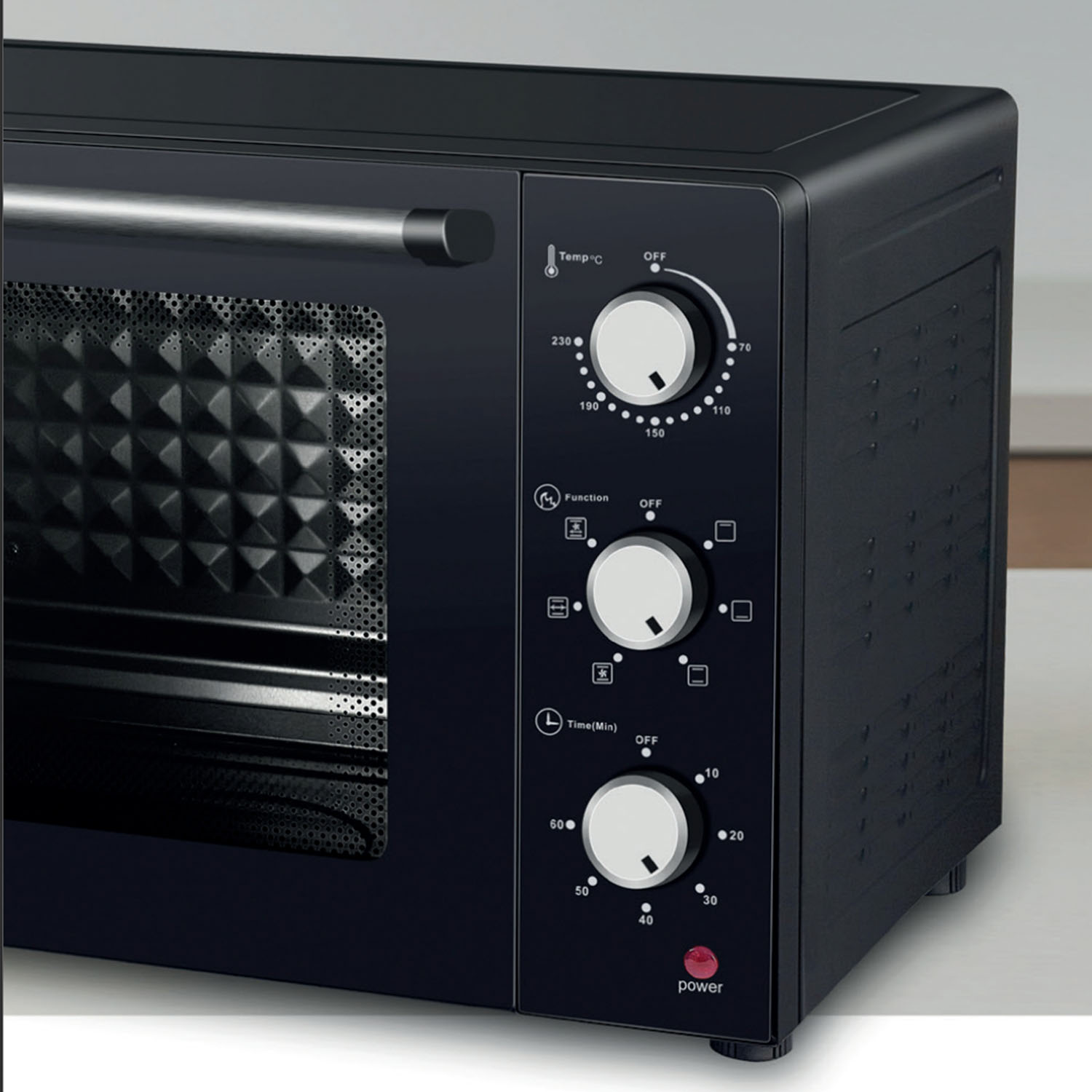 Un mini horno negro con tres mandos plateados para temperatura, función y tiempo en el panel frontal.