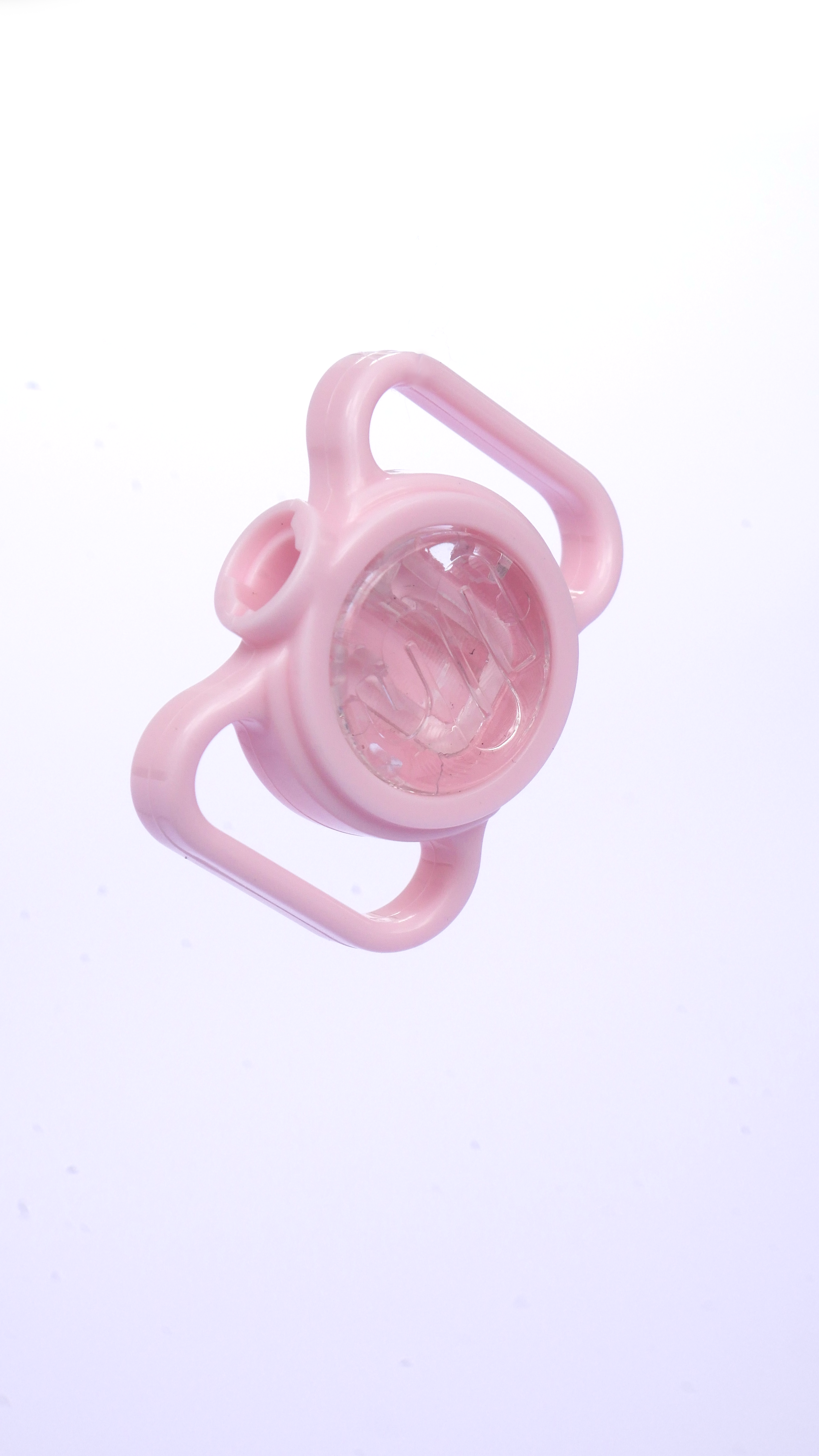 Un vaso de plástico rosa con dos asas y un centro transparente flota sobre un fondo blanco.