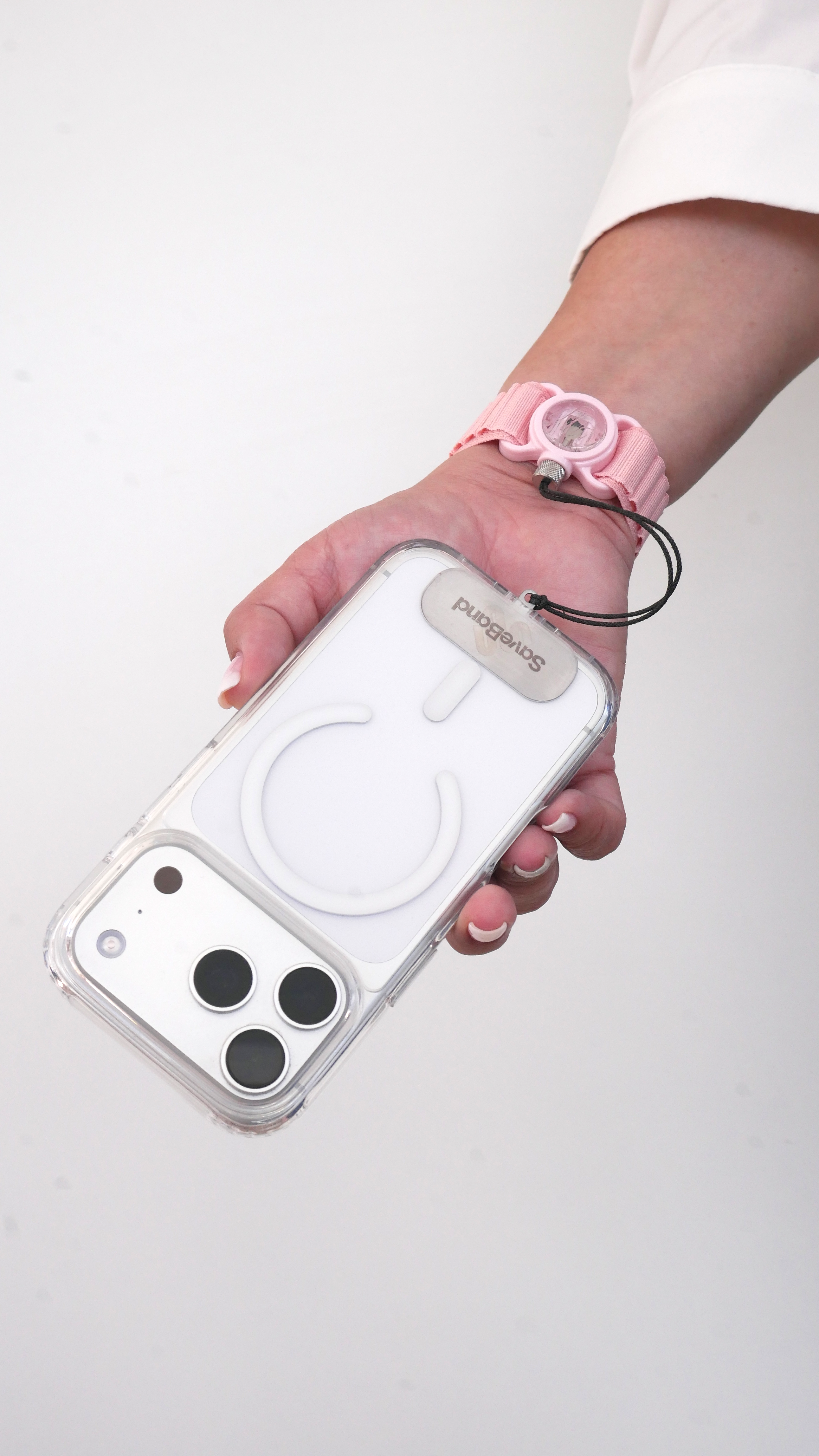 Mano sosteniendo un smartphone en funda transparente con cordón y pulsera rosa.