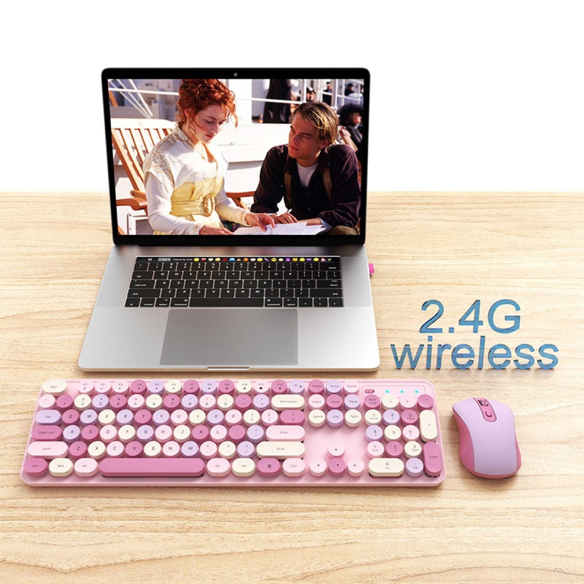 Ein silberner Laptop, eine rosa Funktastatur und eine rosa Computermaus stehen auf einem Holztisch.