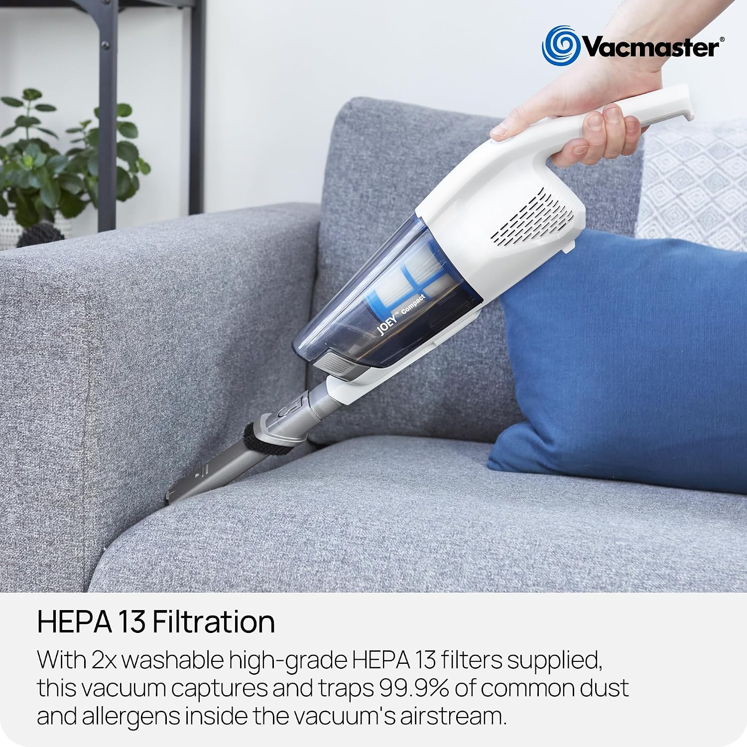 Eine Person benutzt einen weißen Vacmaster Handstaubsauger auf einem grauen Sofa.